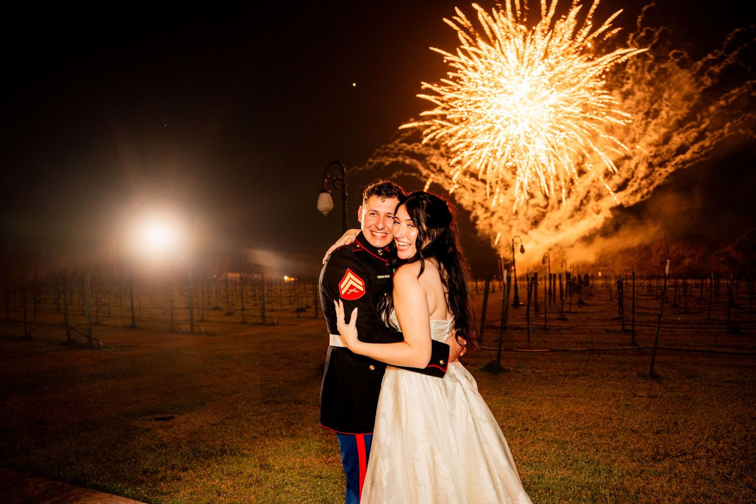 Couple shares romantic moment with fireworks display in background during nighttime celebration.