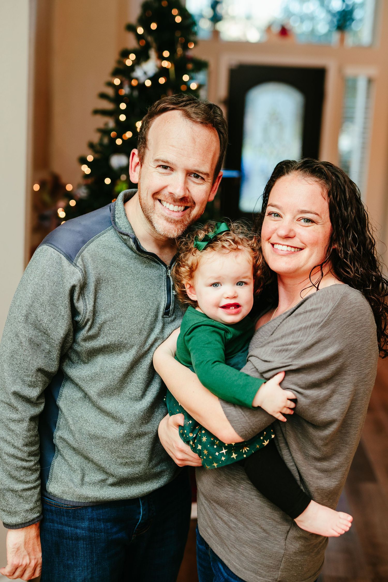 A warm family portrait in front of a lit Christmas tree during the holiday season.