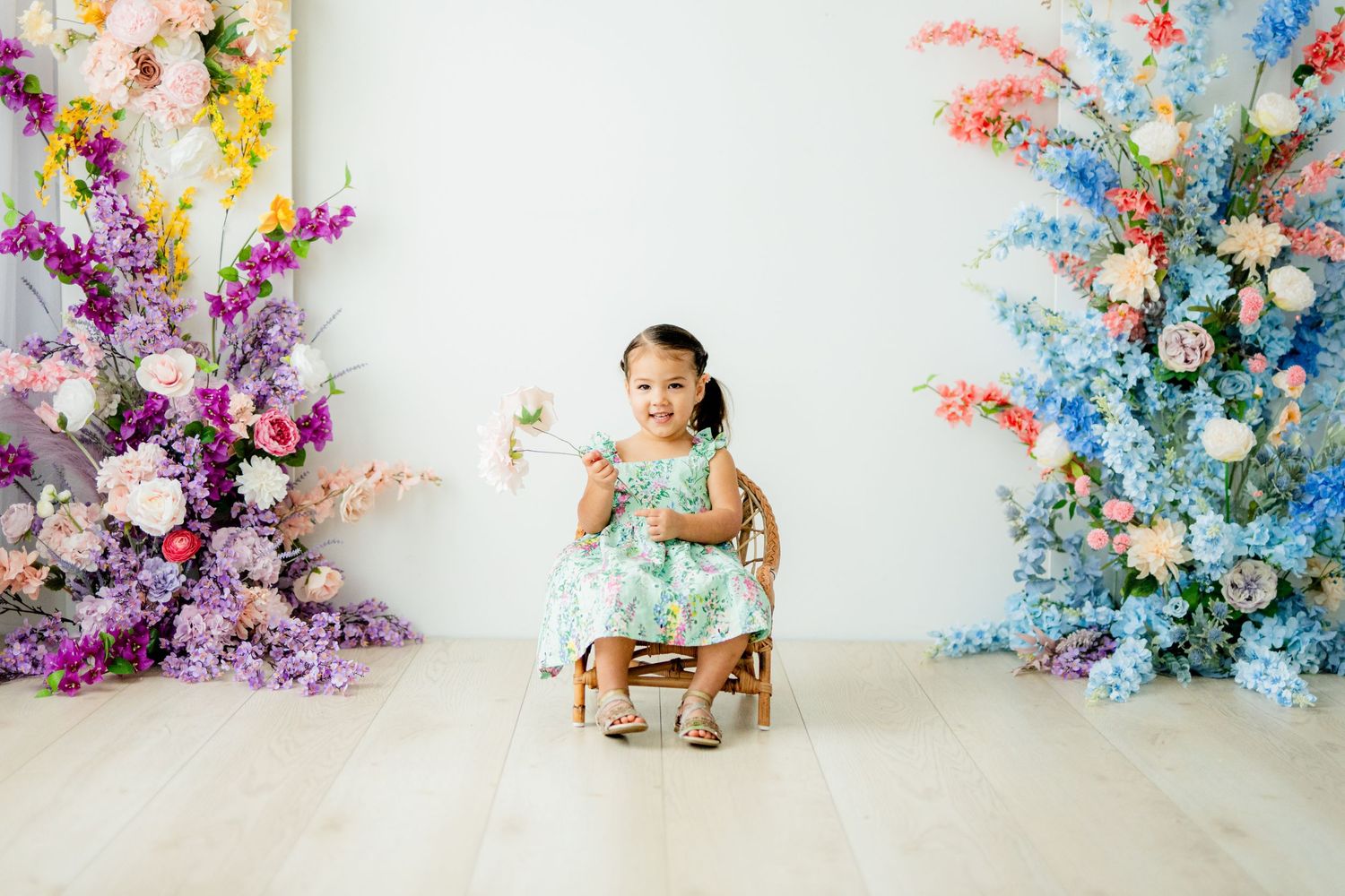 Colorful floral arrangements frame a charming nursery photo setup with vibrant purple and blue blooms.