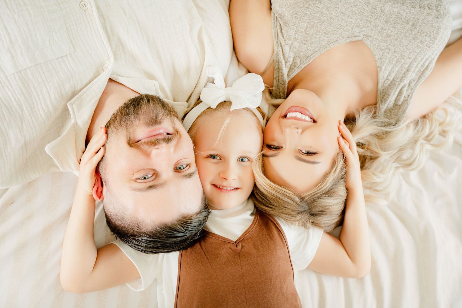 A series of five connected images showing a family lying on a white surface in various relaxed poses.