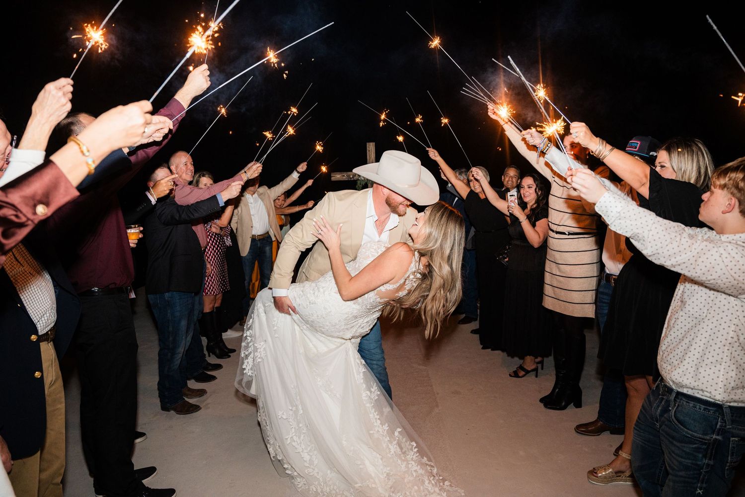 Wedding guests form a sparkler tunnel exit for the newlyweds during an evening celebration.