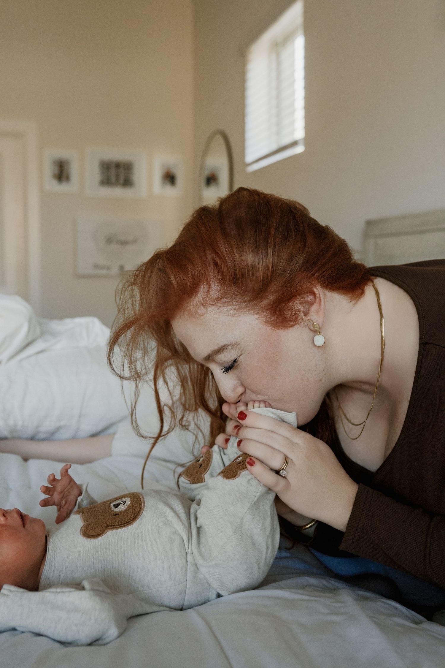 A tender moment between parent and baby on white bedding as they share an intimate interaction in soft natural light.