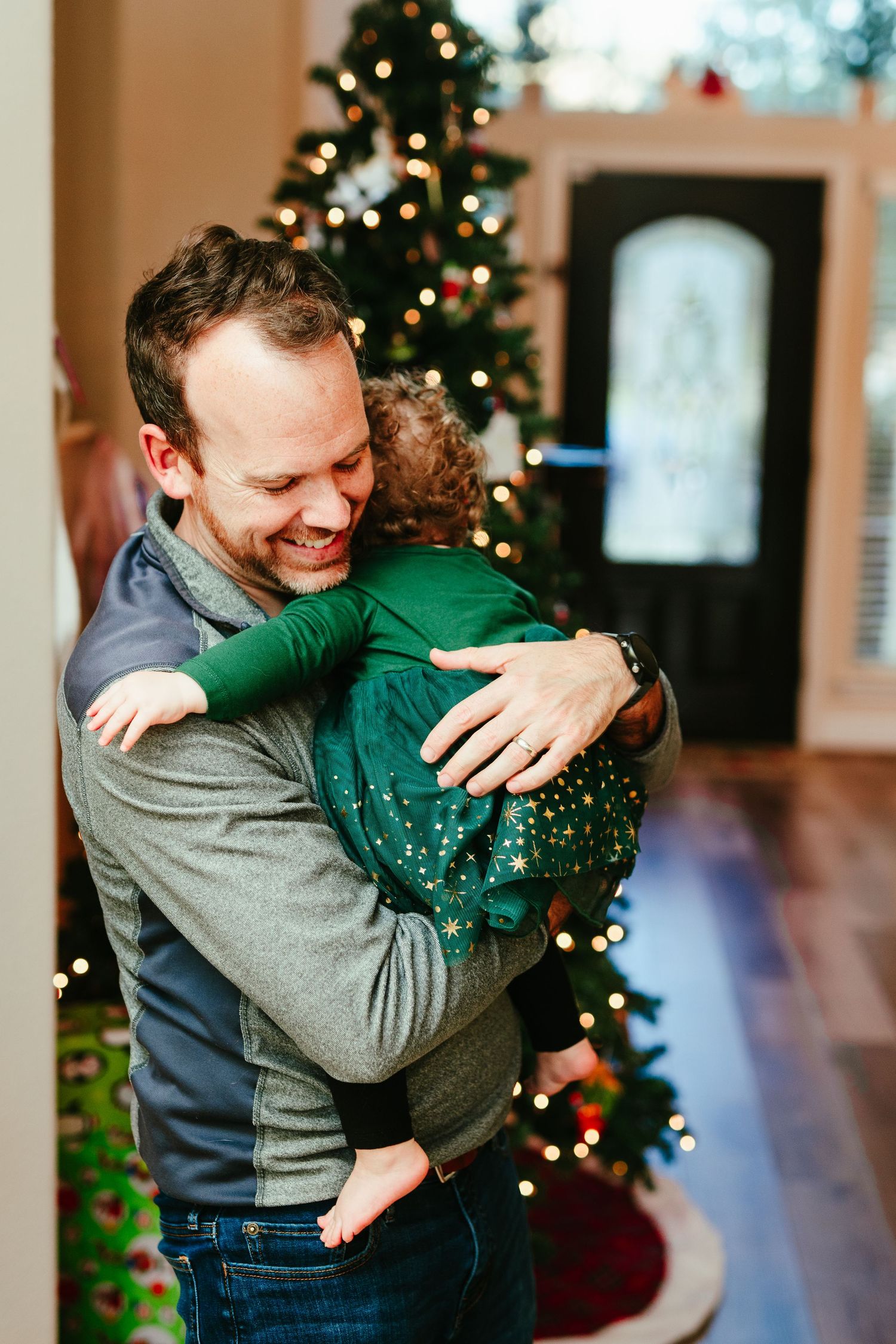 A joyful moment captured during Christmas time with a decorated tree in the background.