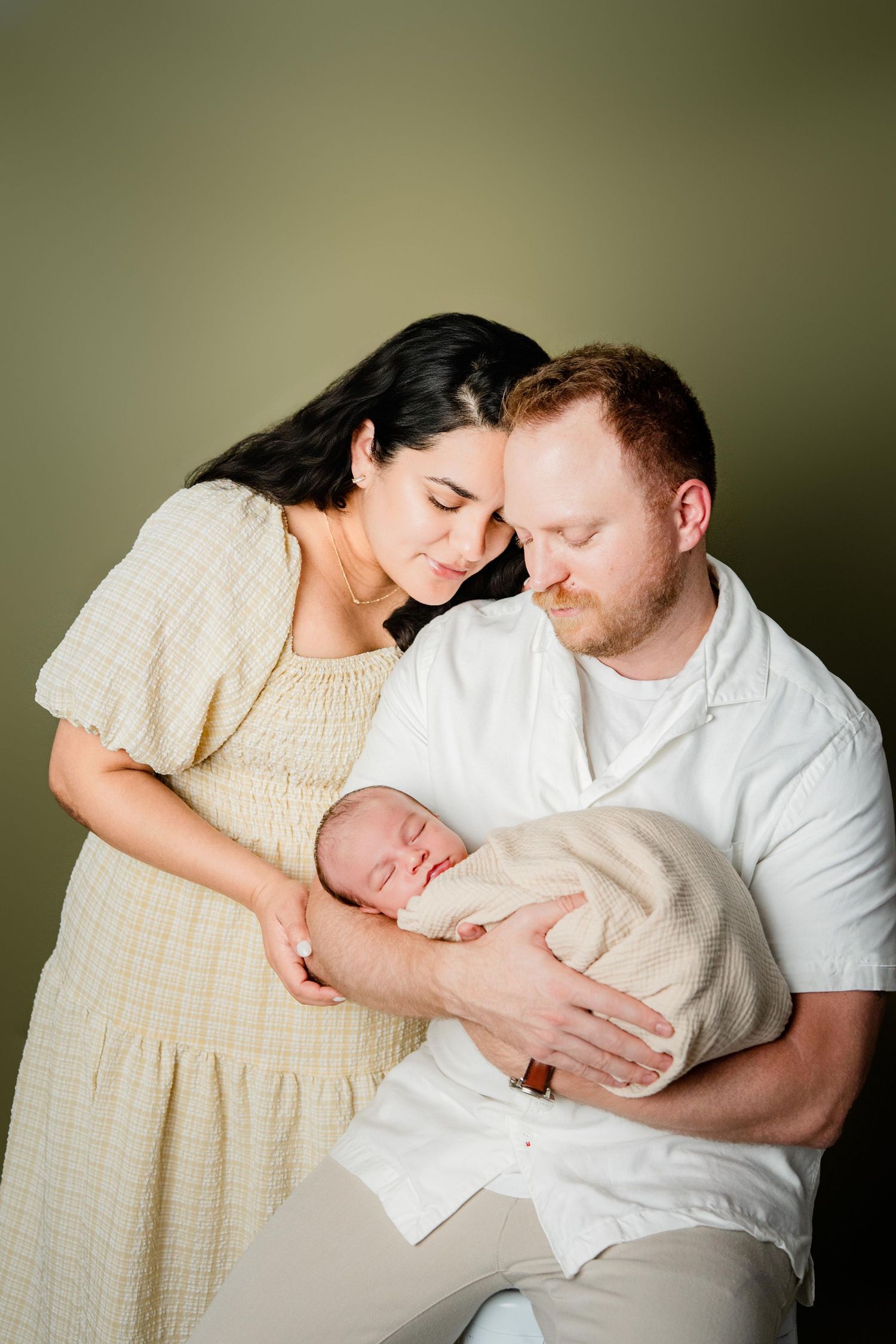 A tender family moment shared between parents and their newborn baby in gentle natural lighting.