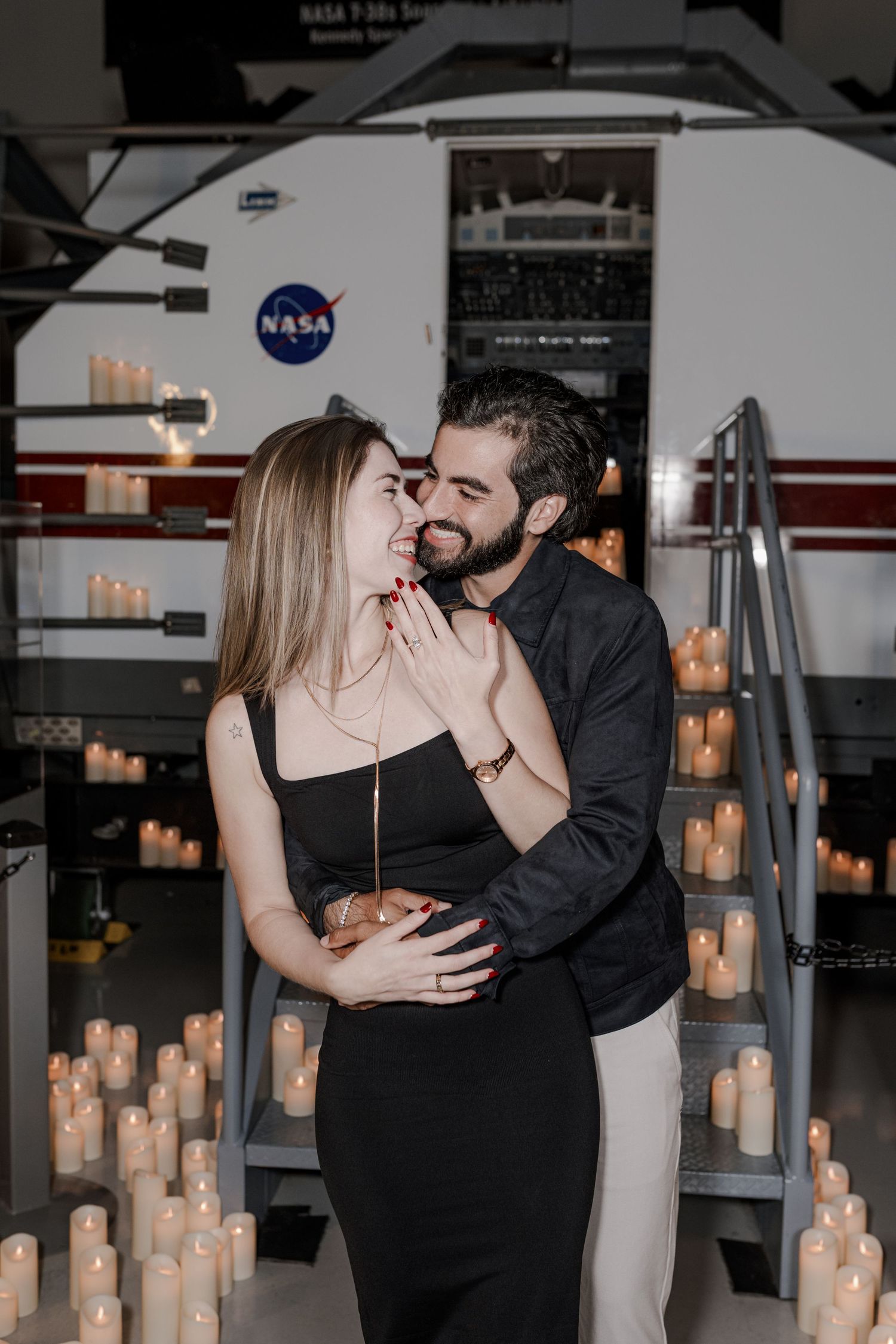A couple shares an intimate moment while dancing together surrounded by glowing candlelight in an elegant indoor space.
