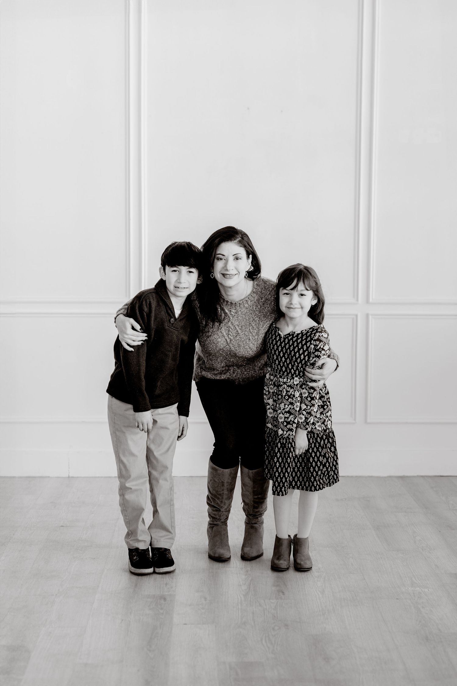 Black and white portrait of three people posing against a white wall.