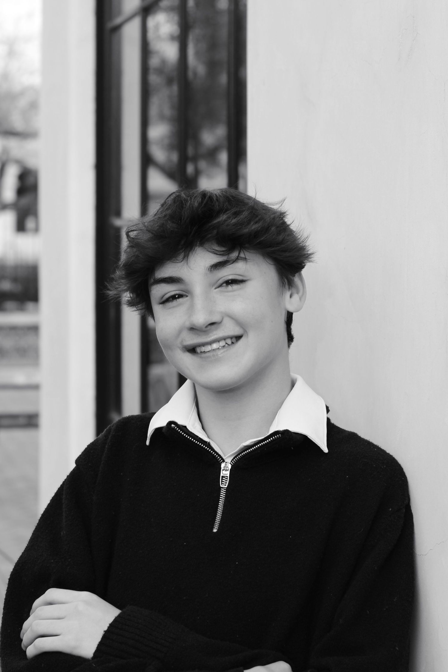 Black and white portrait of a casual person against a white wall.