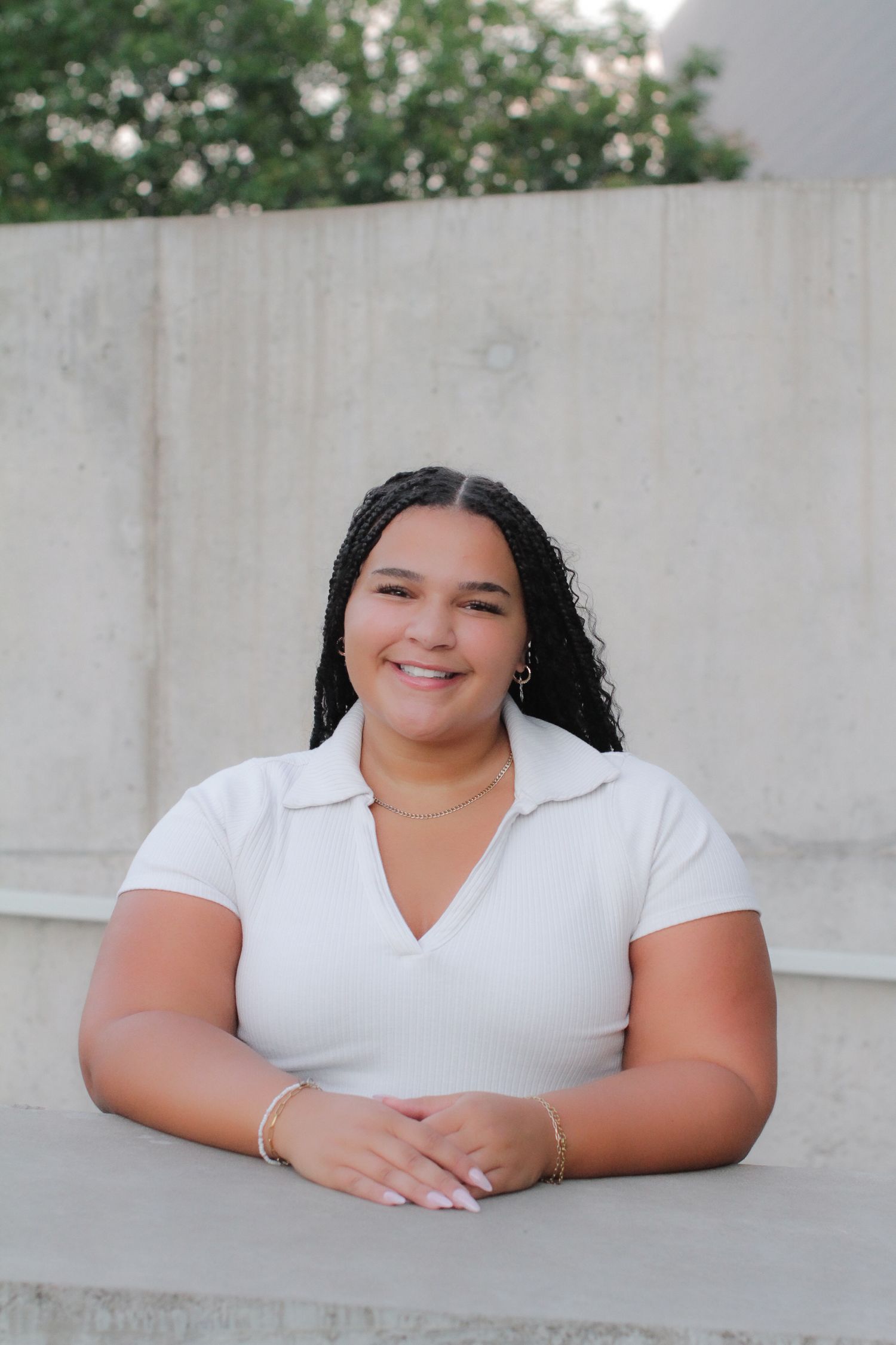 A series of portraits of a person in a white top sitting at a white concrete wall.