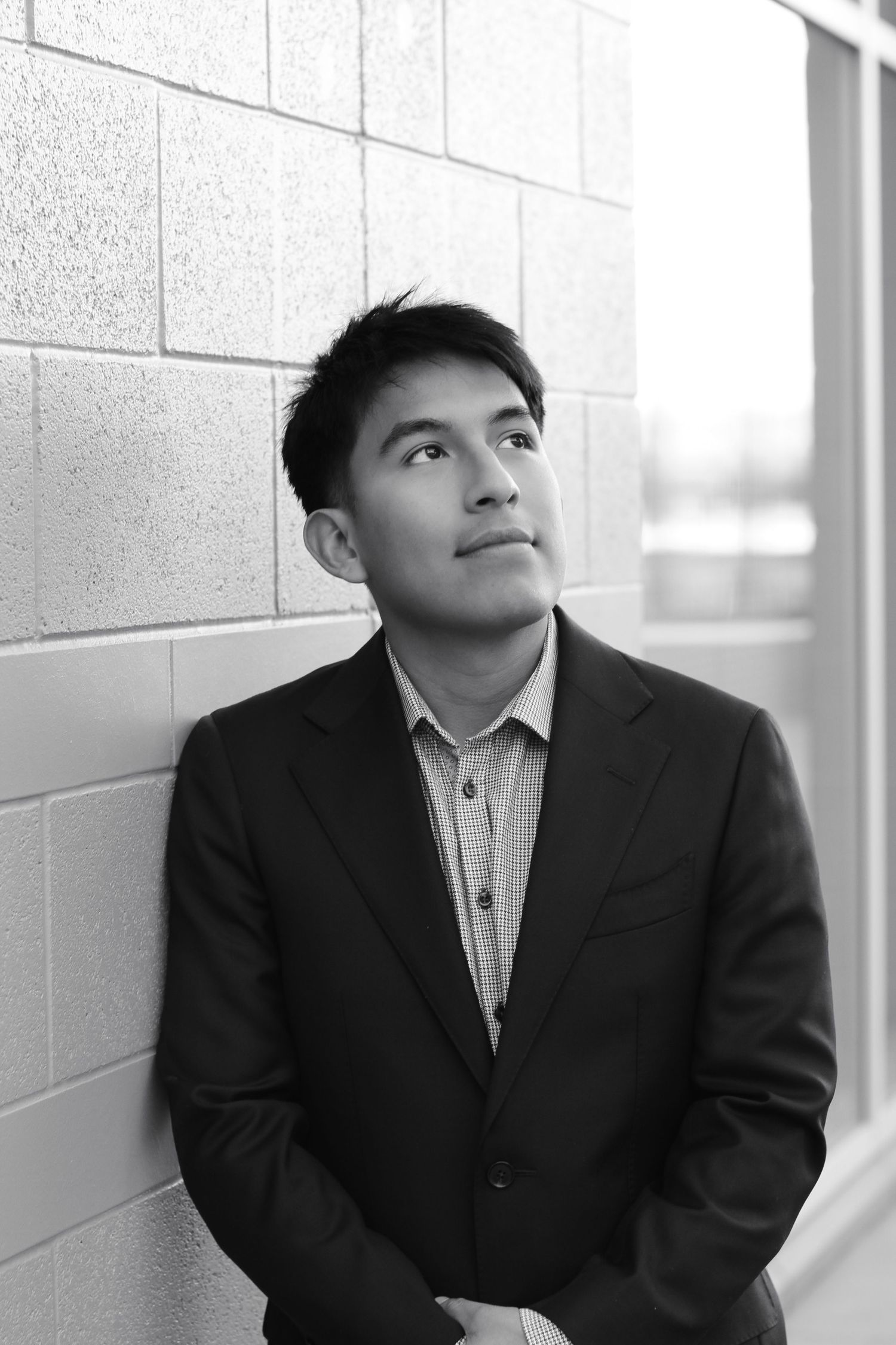 Professional portrait in suit looking upward against concrete wall background.