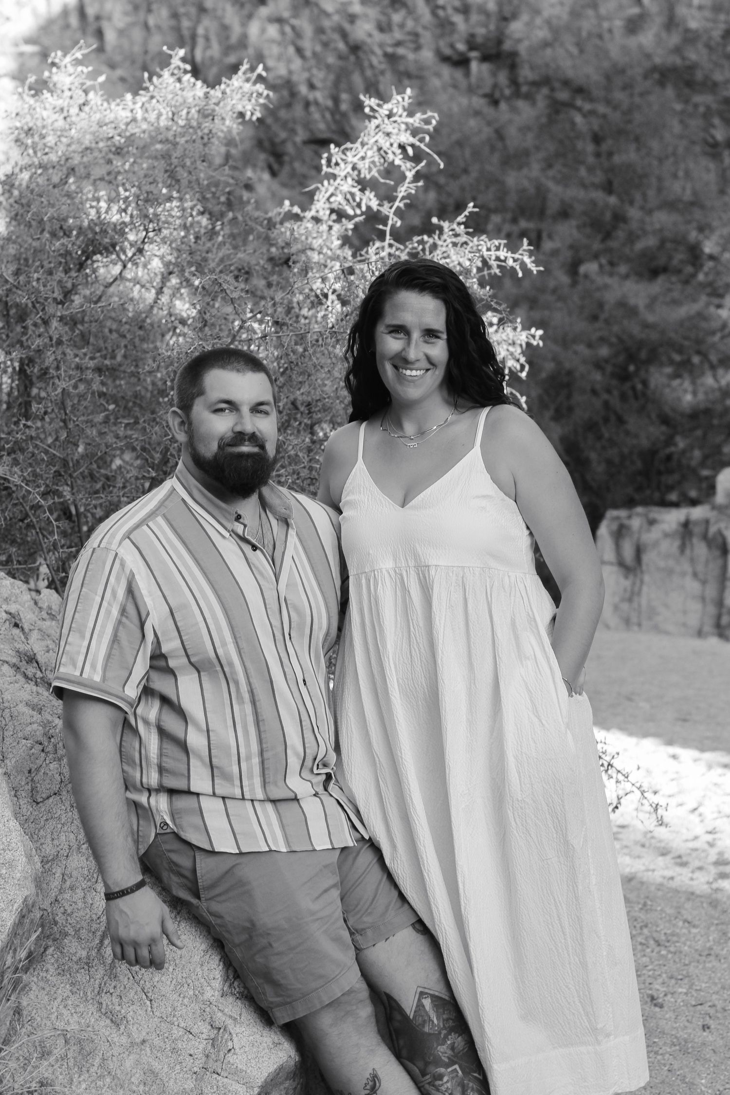 A couple dressed in white and stripes poses for casual outdoor photos.