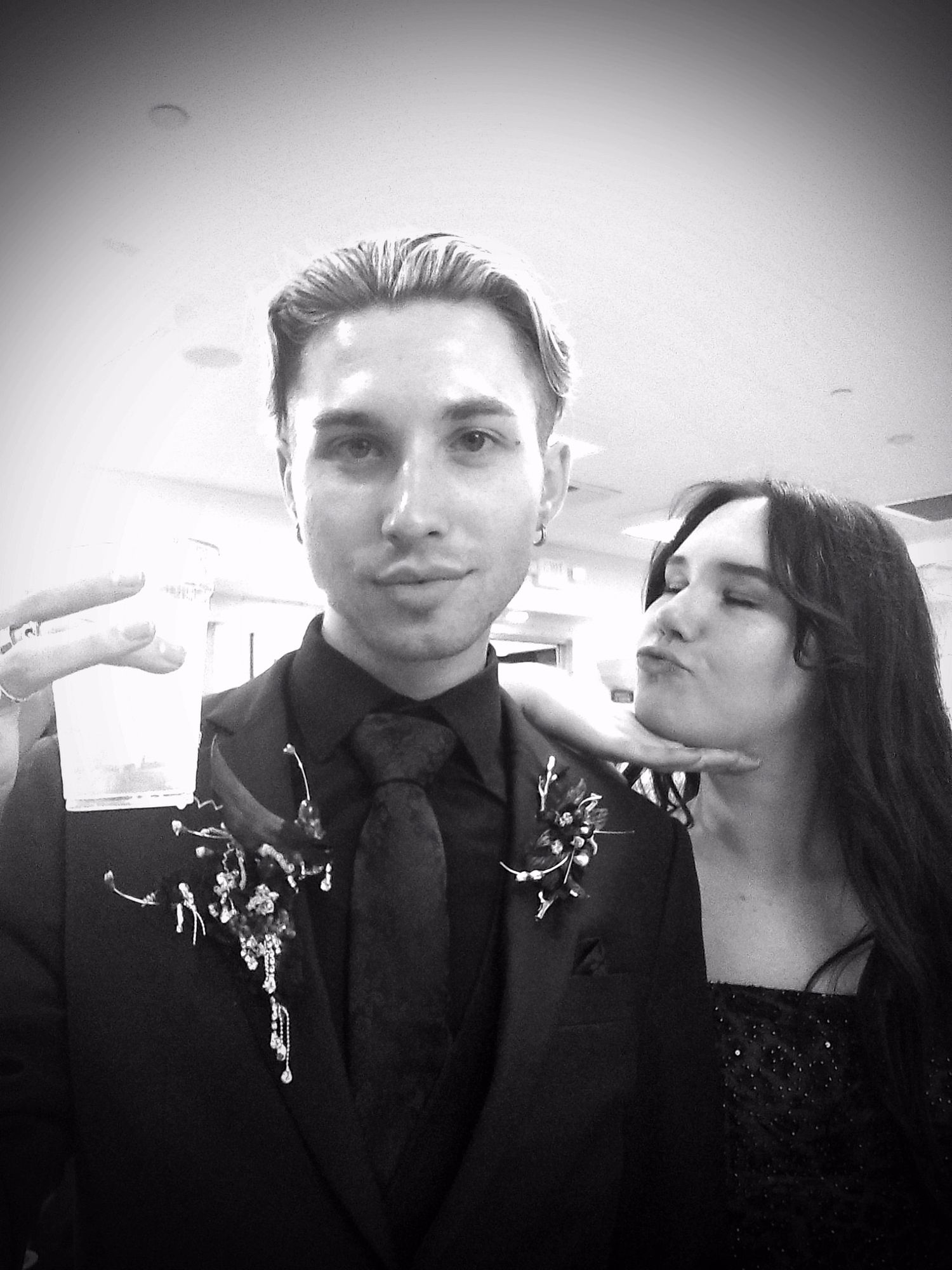 Black and white photo of a couple in formal wear posing playfully at a wedding event.