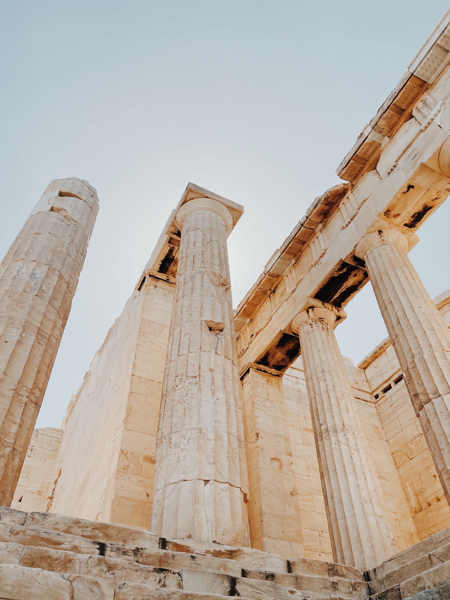Ancient Greek stone columns photographed from below against a bright sky.