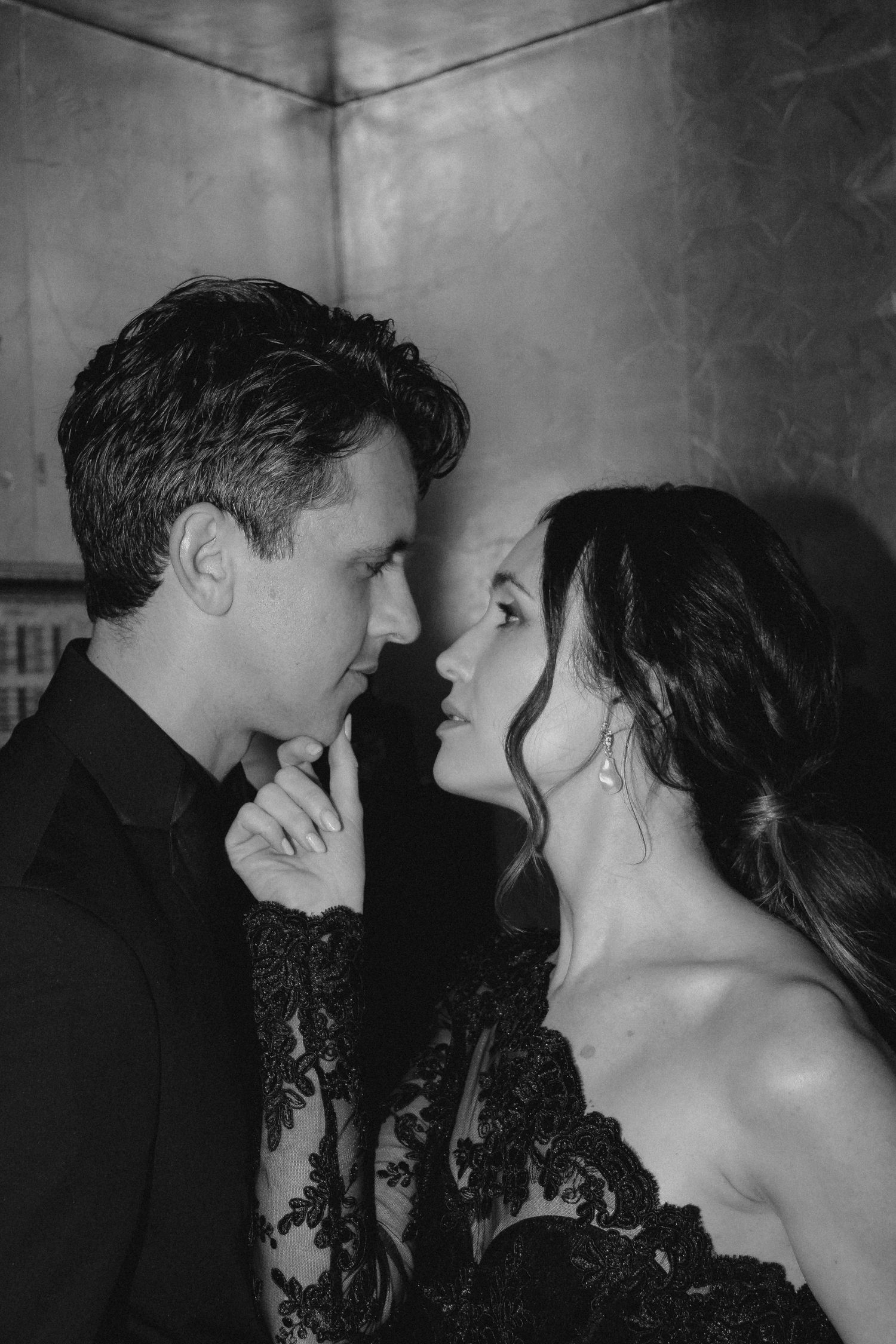 Romantic black and white portrait of couple in formal wear sharing close intimate moment.