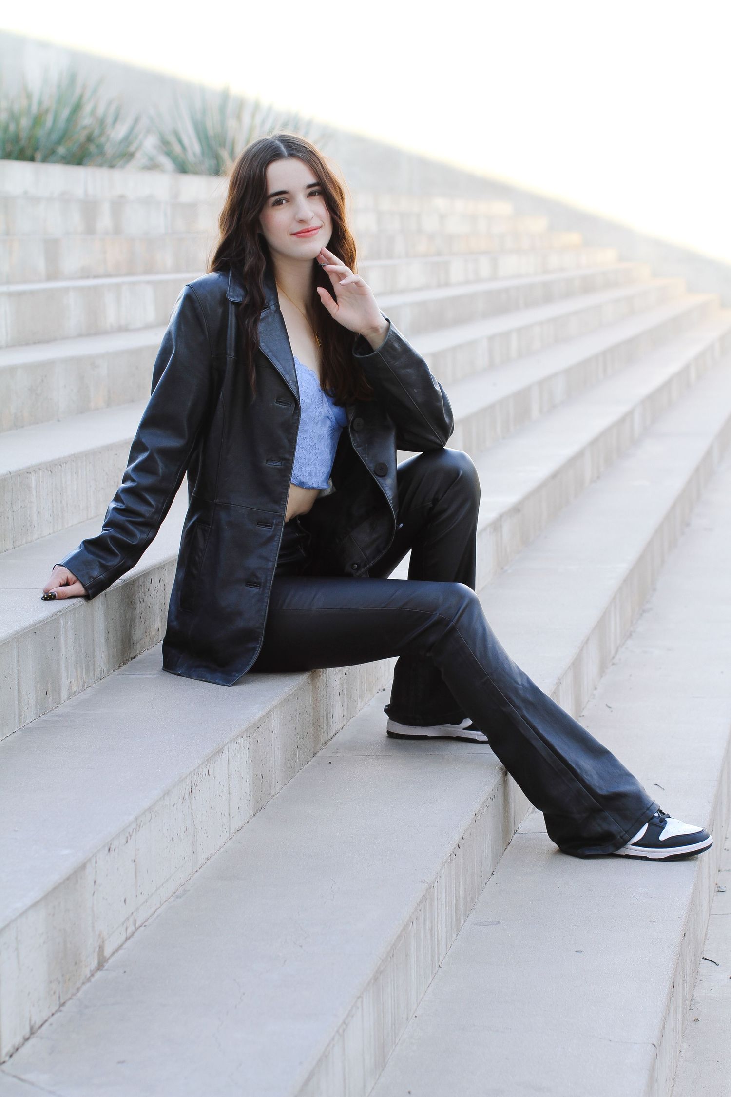 Fashion photo of a model in black leather jacket posed on concrete steps.
