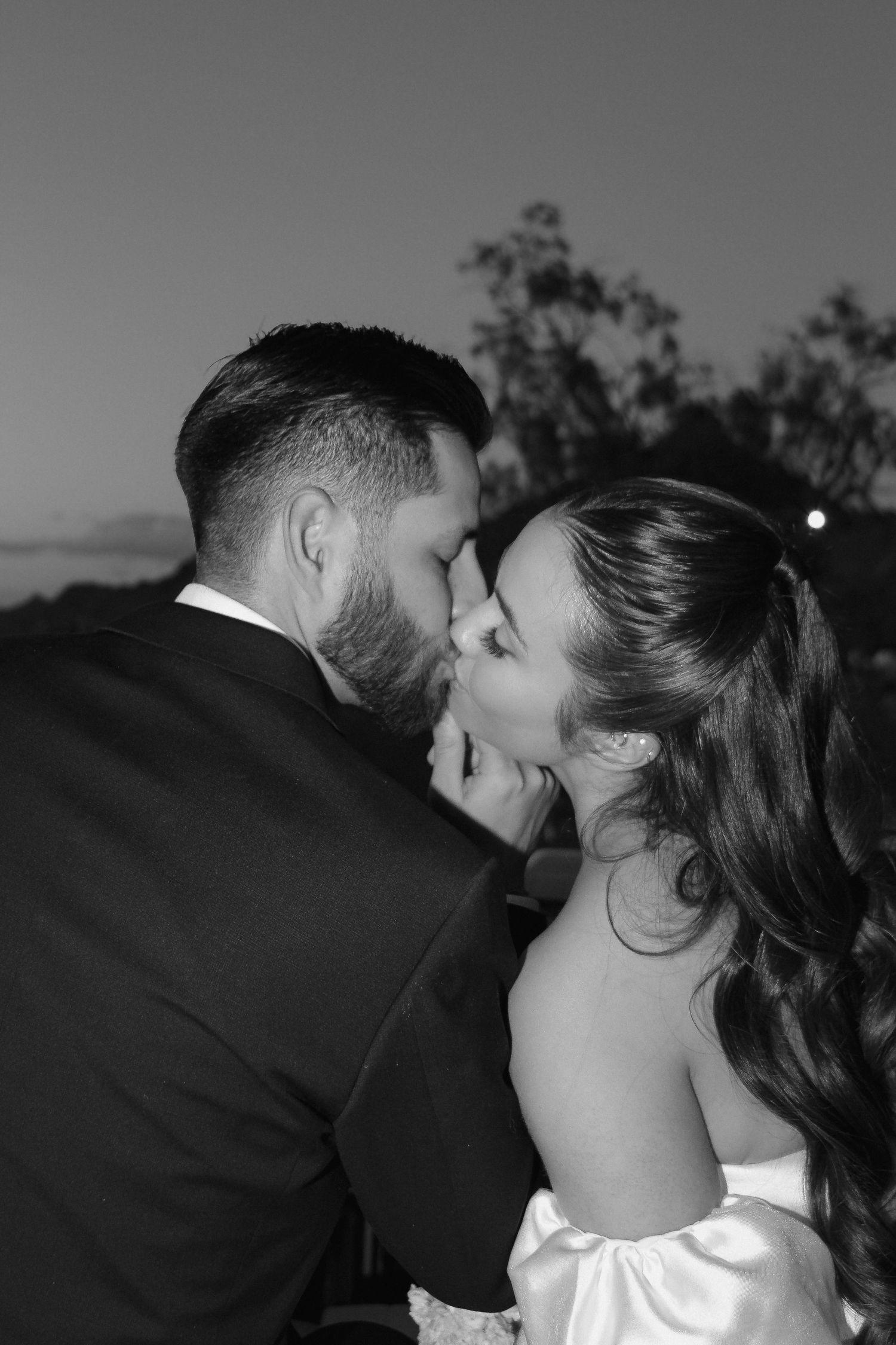 Black and white close-up of couple sharing tender moment at dusk.