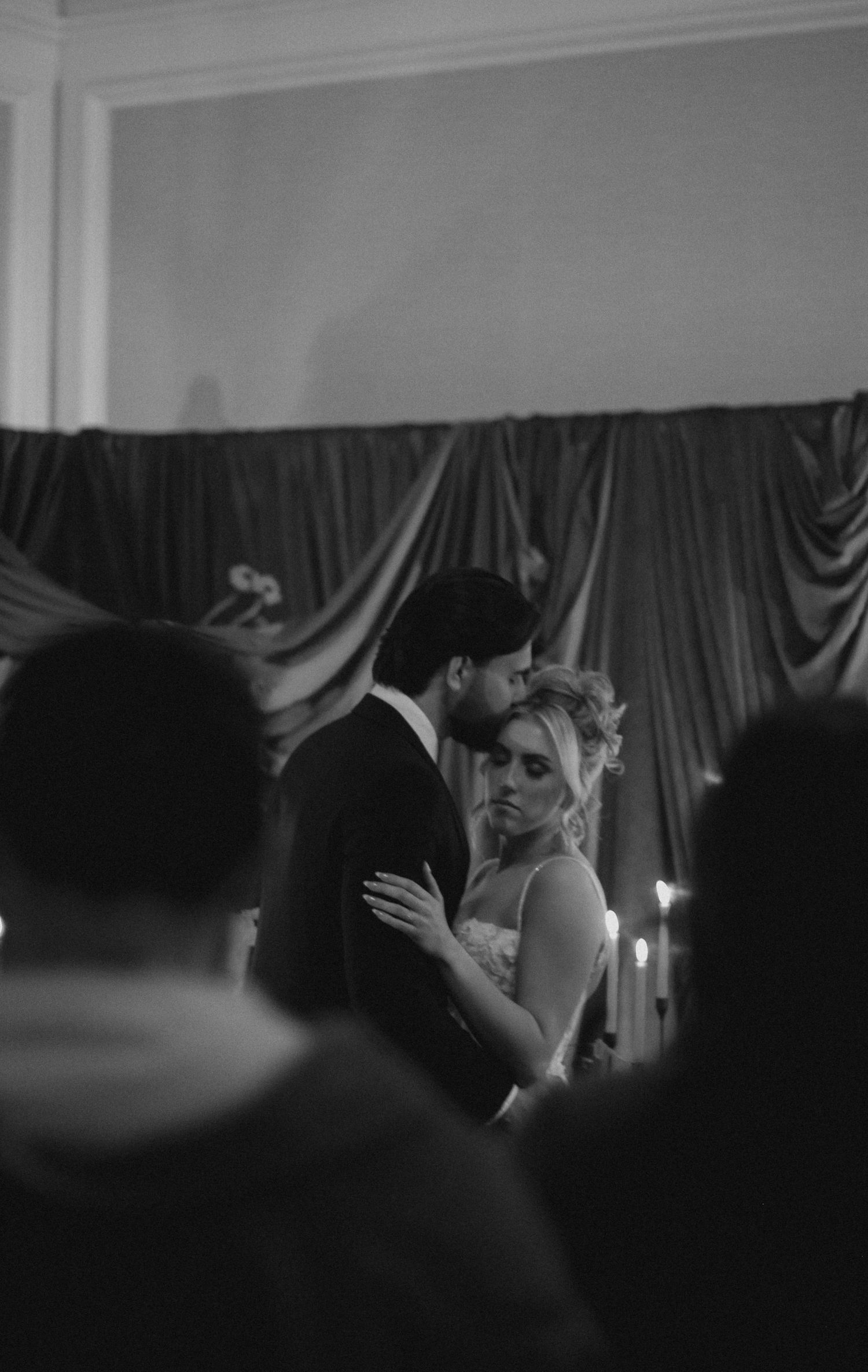 A romantic dance moment captured in black and white with candlelight and draped fabric backdrop.