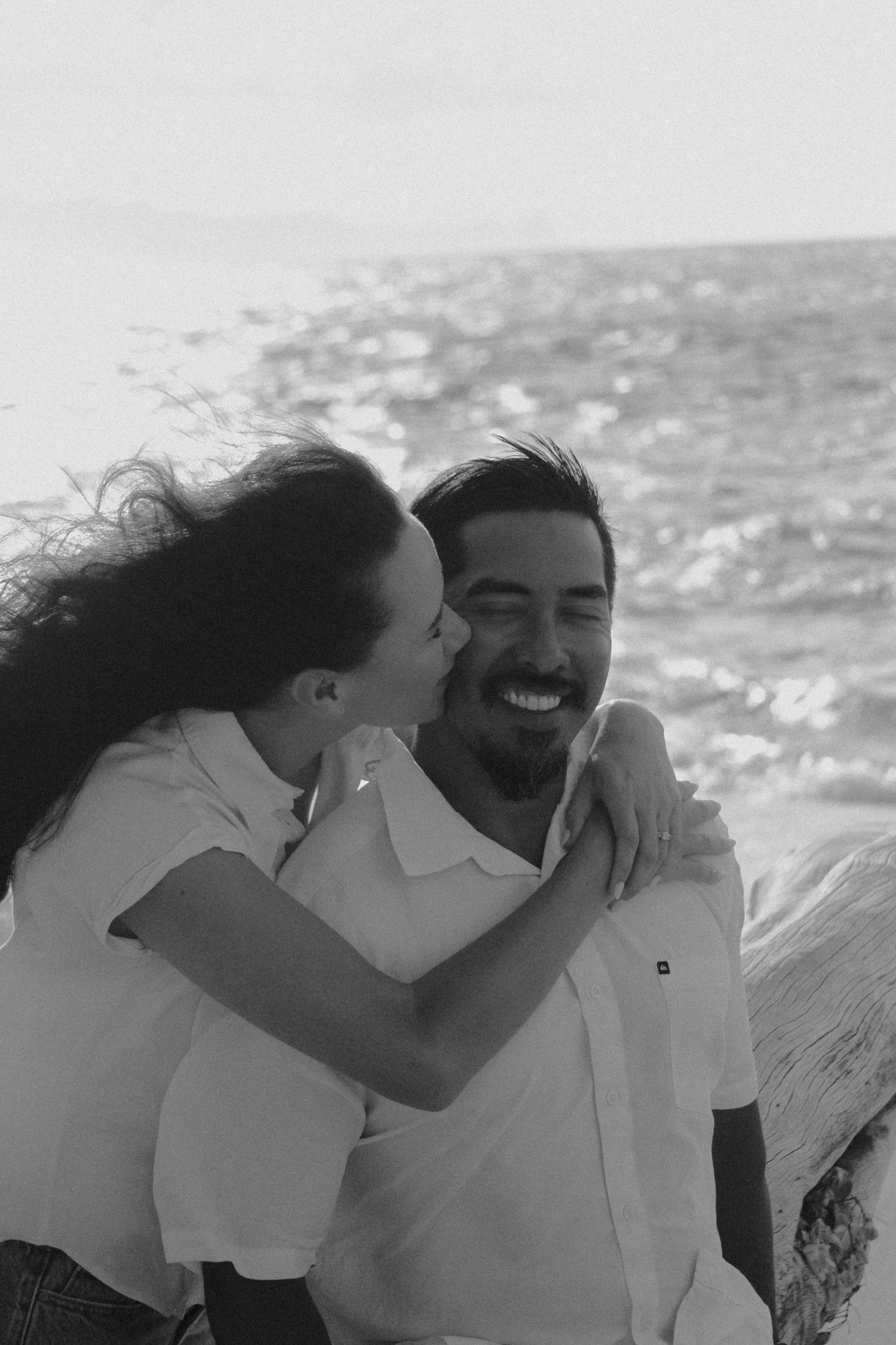 A couple shares an intimate moment together on a boat with sparkling water in the background.