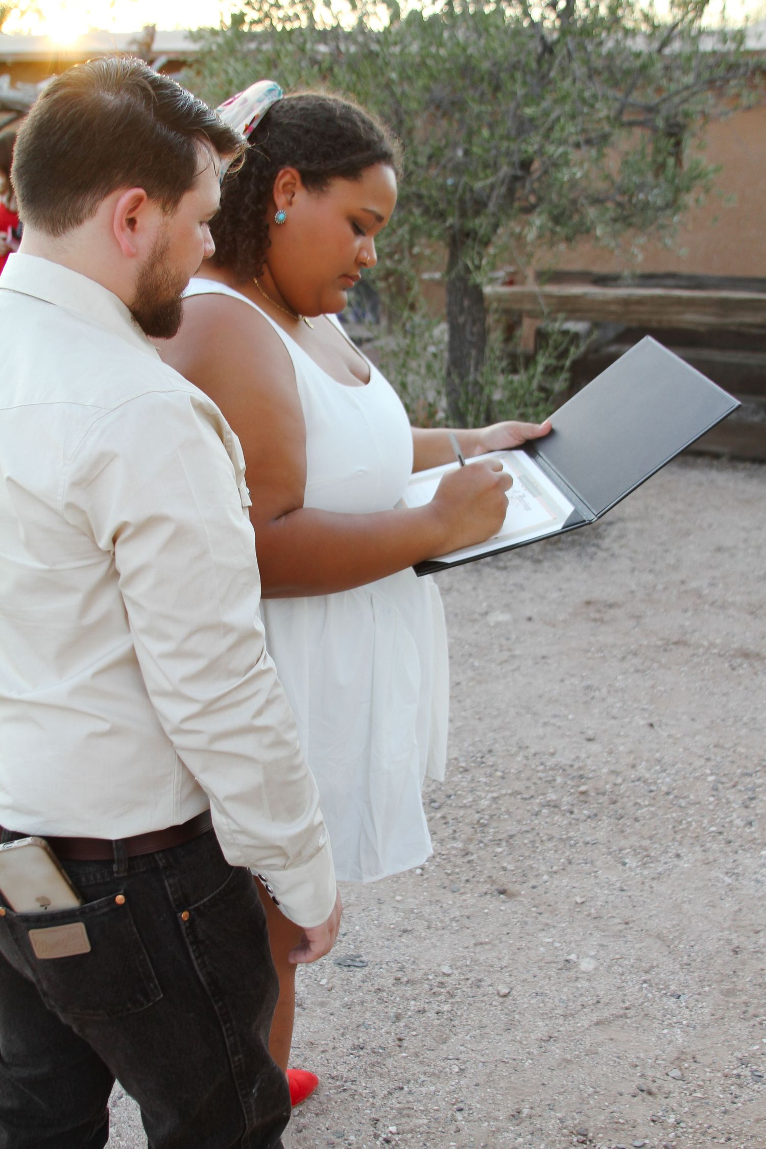 Couple reads from papers during outdoor ceremony with desert backdrop.