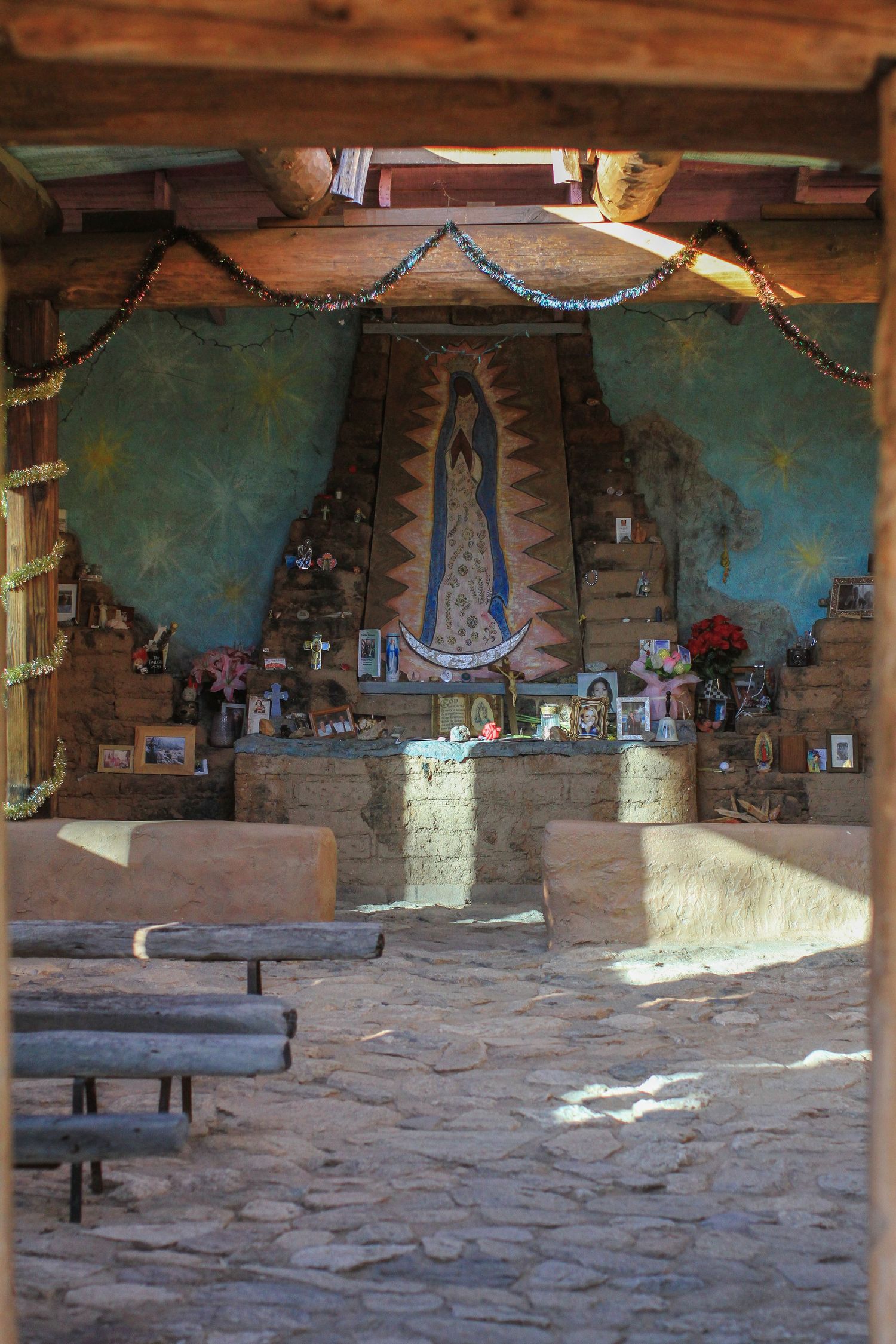 Chapel interior with religious shrine featuring blue mural, string lights and southwestern decor.