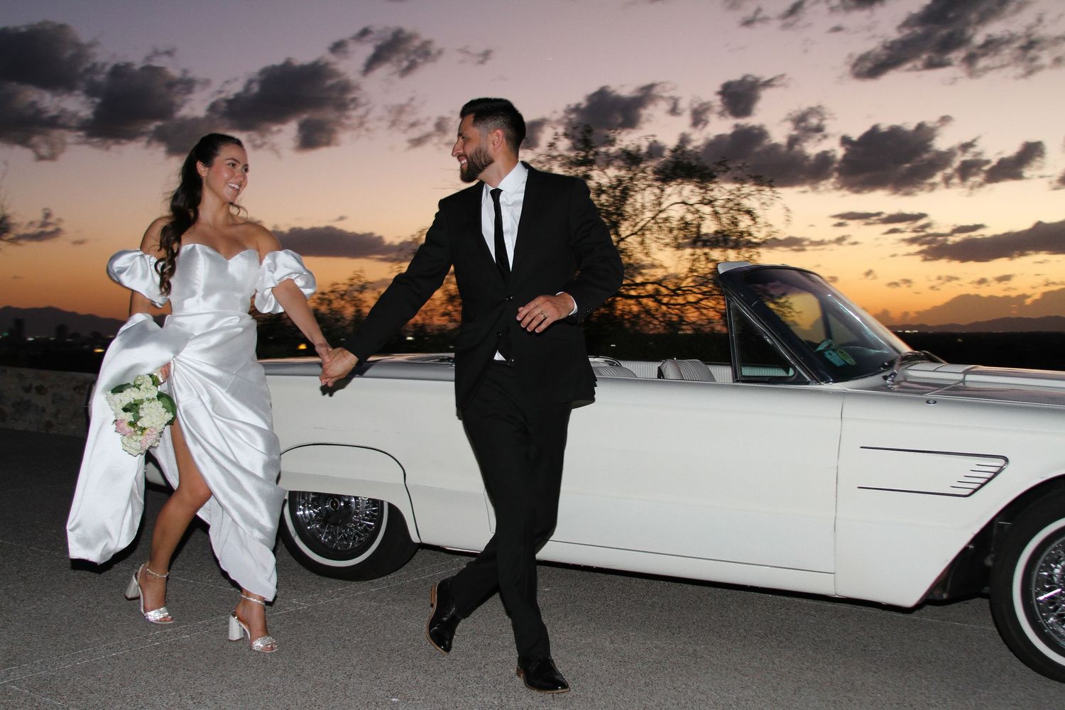 Romantic sunset photos with vintage white car featuring elegant formal attire.