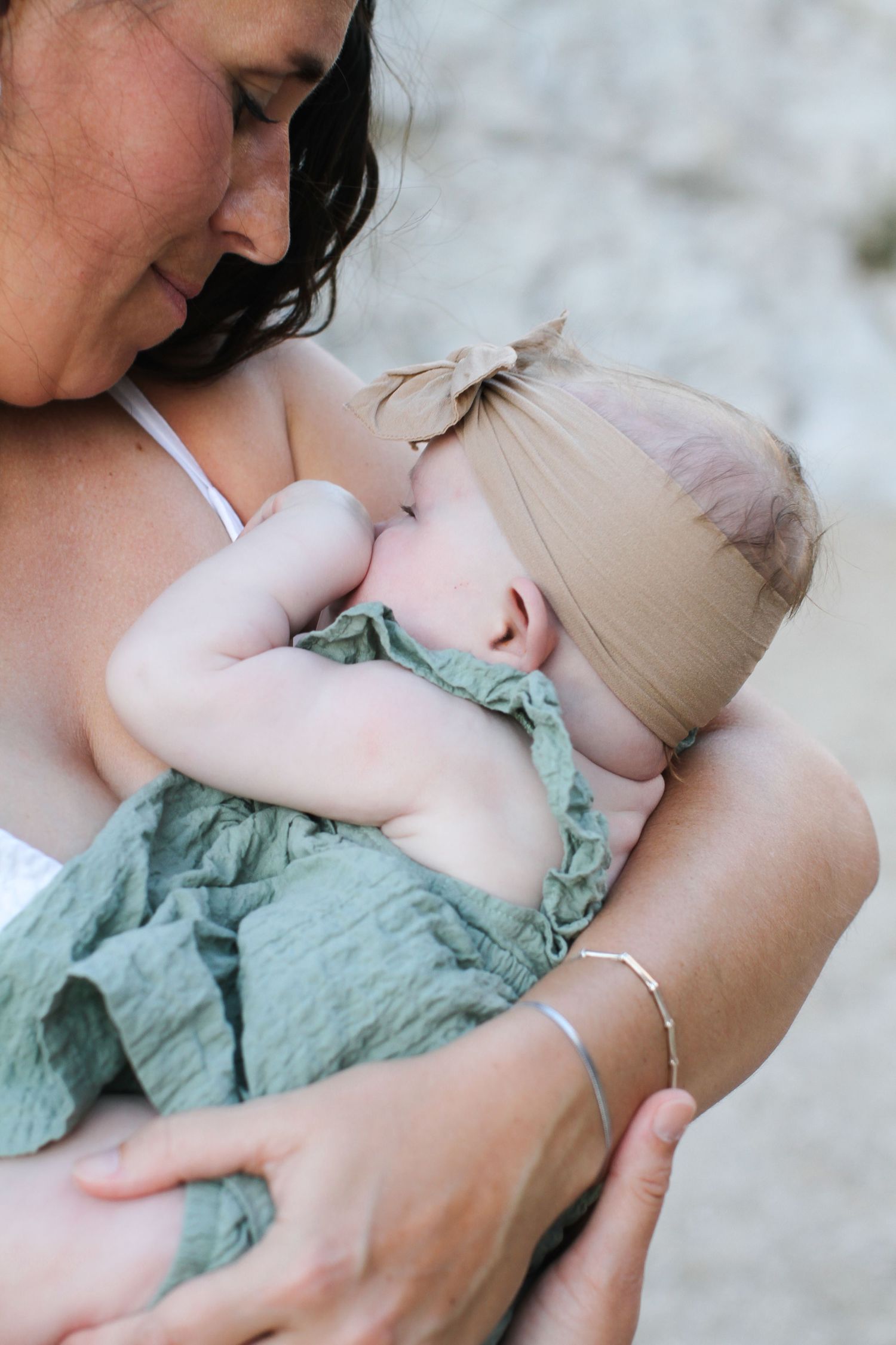 Tender moment between parent and baby in mint green outfit.