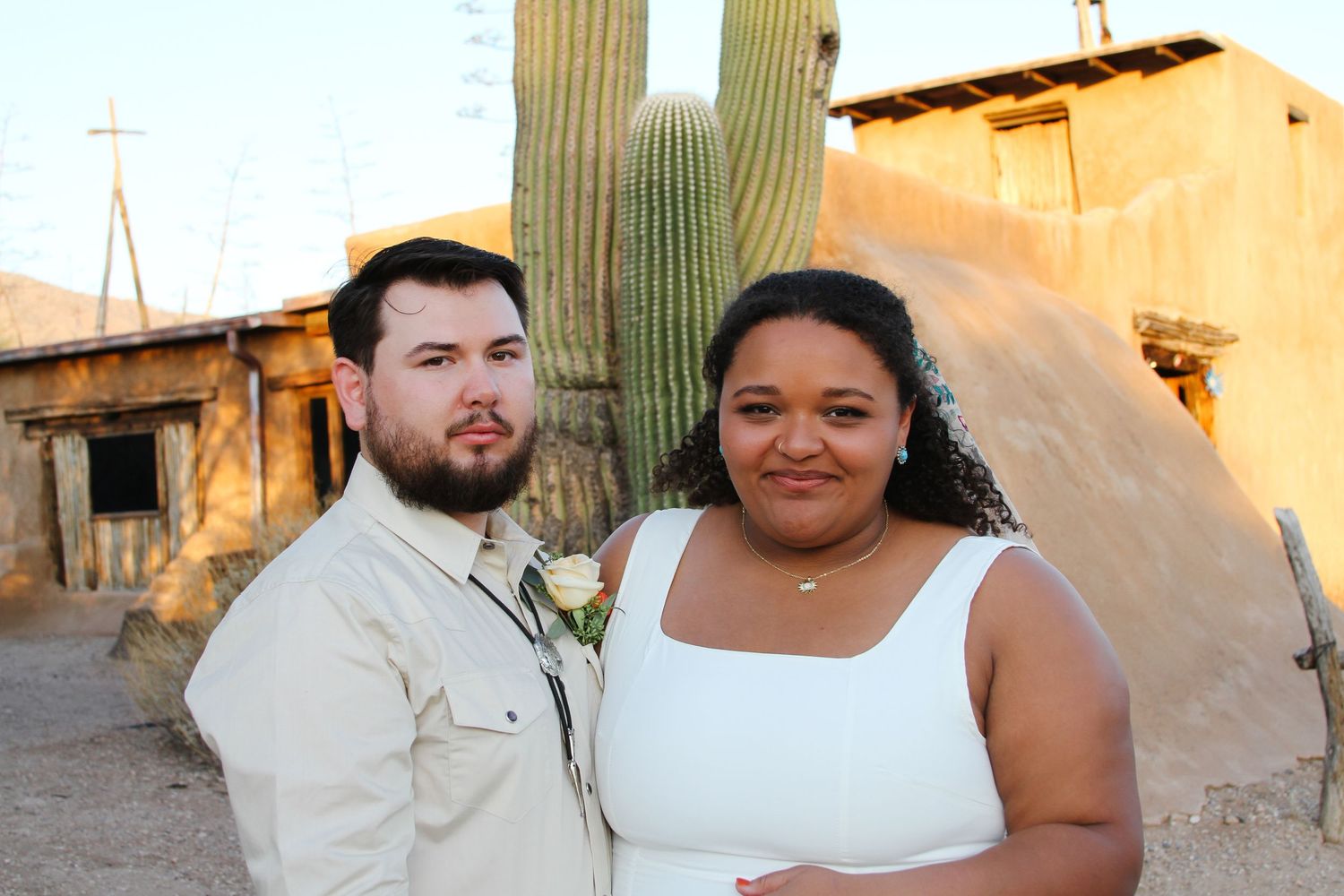 Newlyweds pose for a portrait against a southwestern desert landscape.