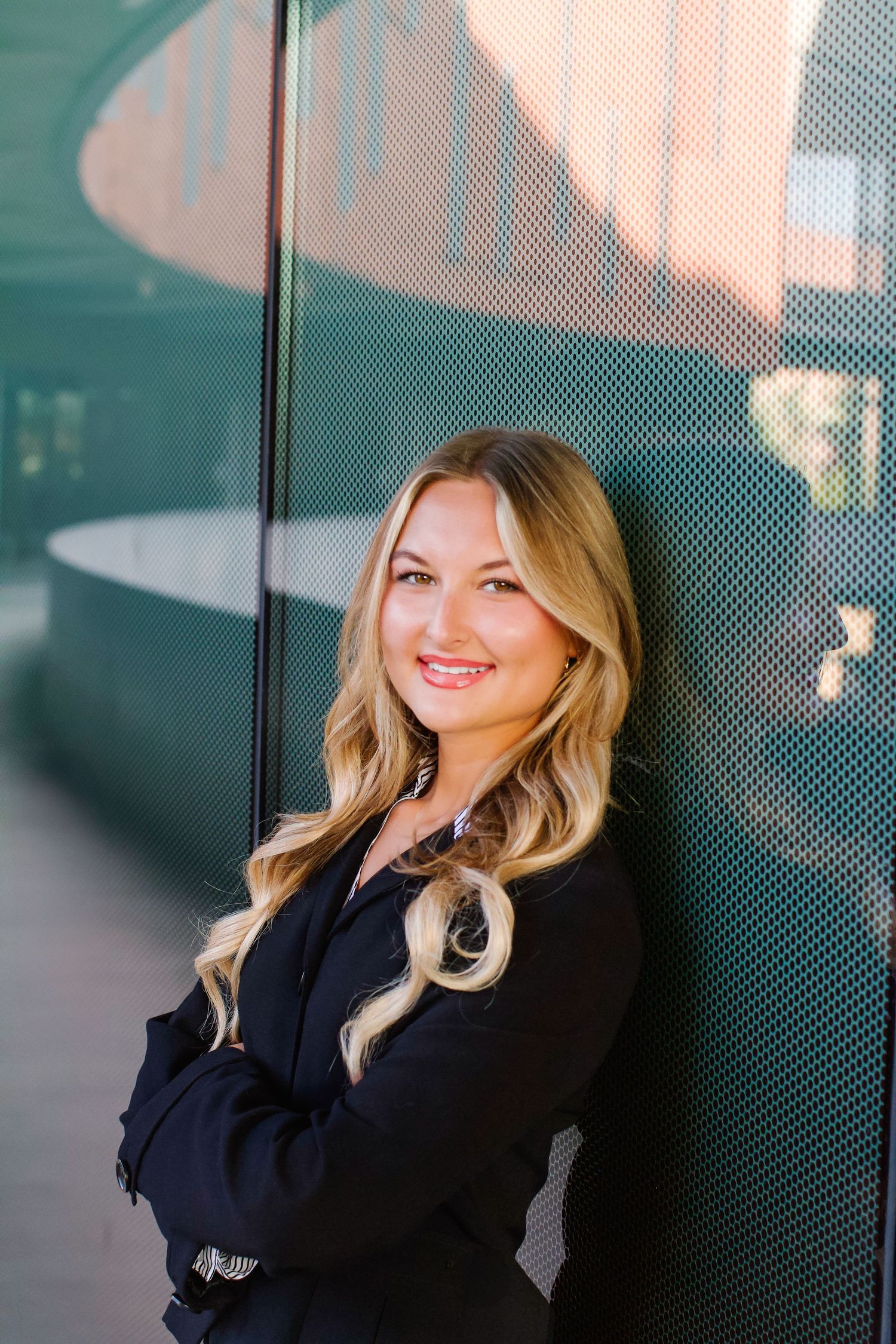 Professional woman in navy blazer poses against modern office wall in a series of casual headshots. Tyler Garlej Photography