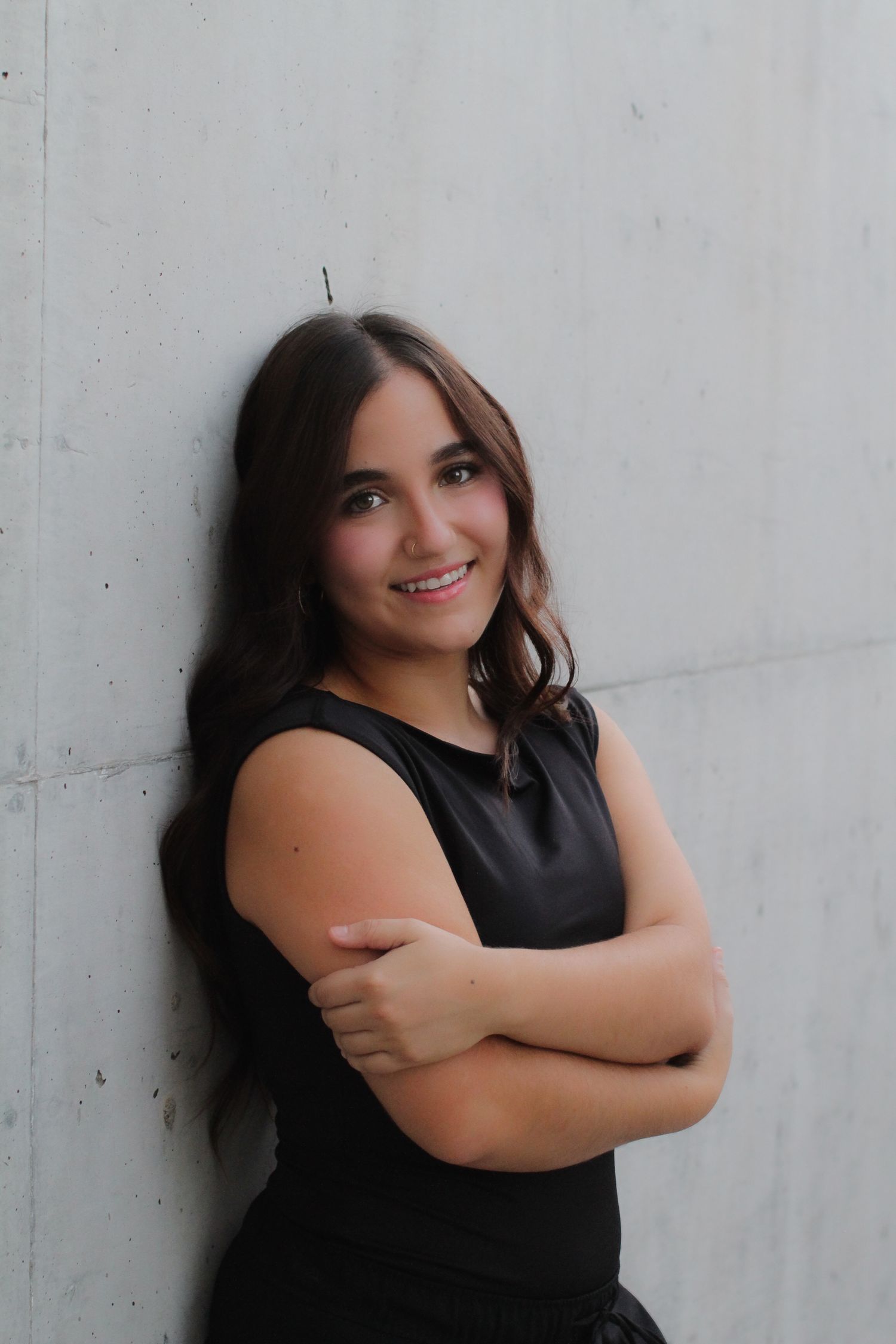A series of portrait poses of someone in black attire against a concrete wall background.