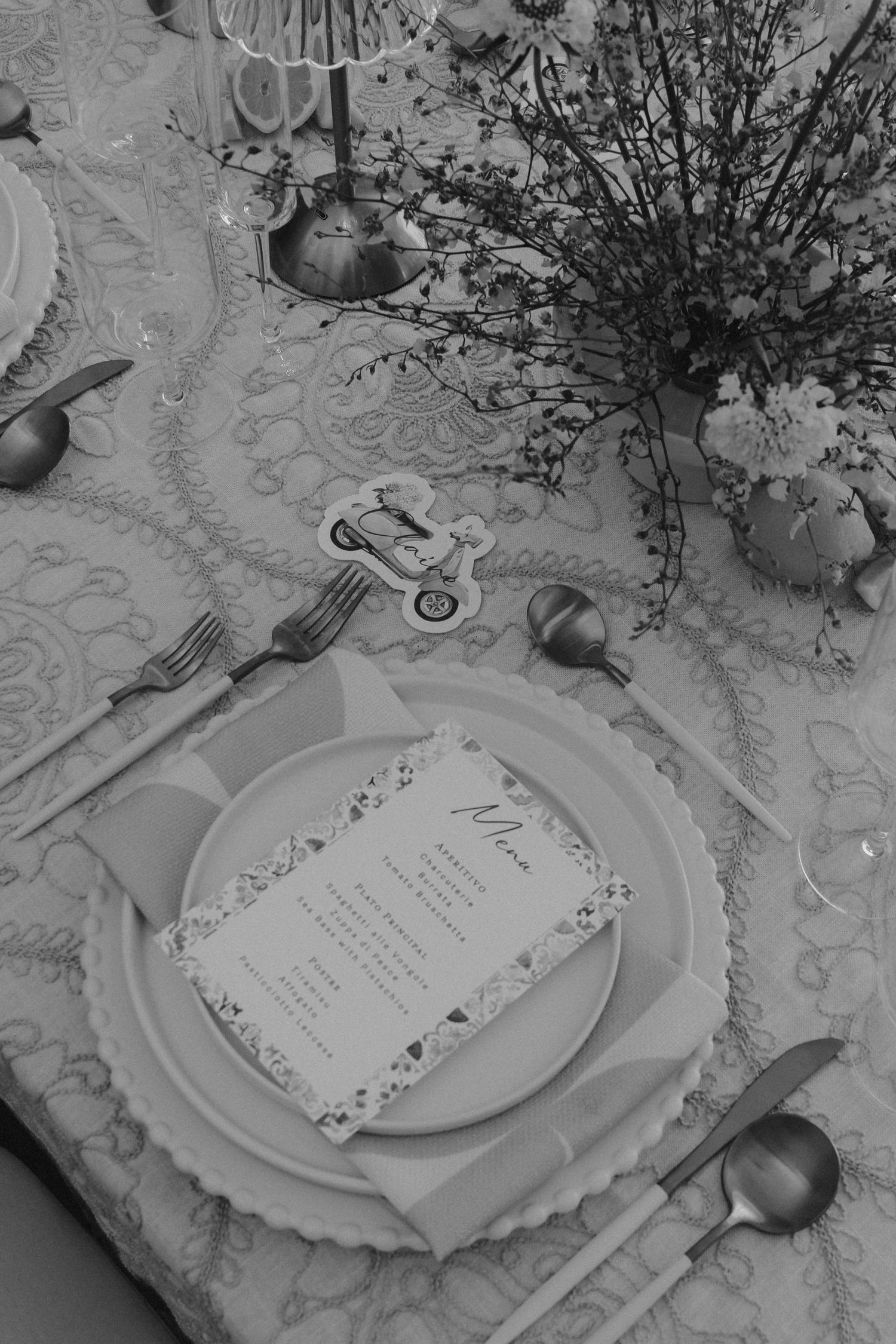 Tyler Garlej Photography -Elegant place settings with menu cards on white plates and floral centerpieces arranged on a patterned tablecloth.