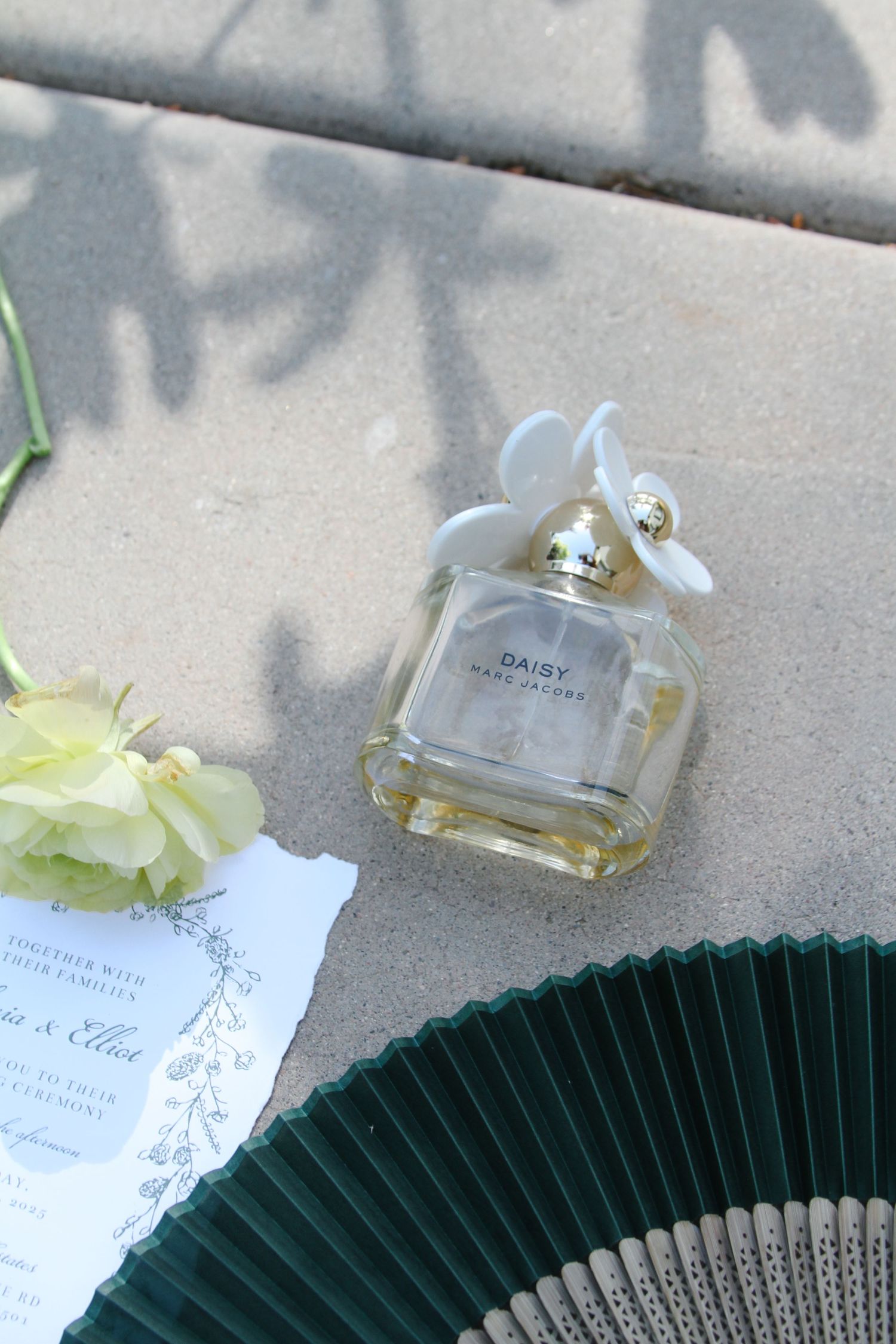 A delicate perfume bottle and folding fan arrangement on a light gray surface with soft shadows. Tyler Garlej Photography