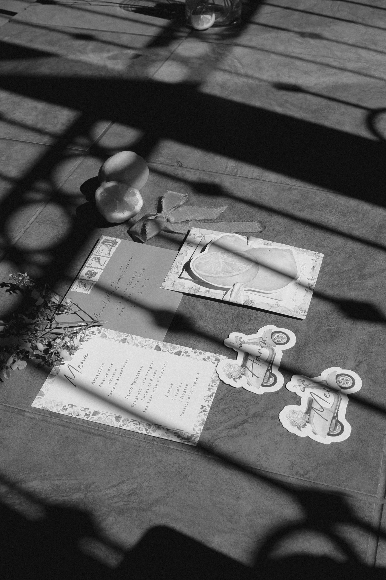 A black and white photo of wedding stationery and decorative elements on a wooden surface.