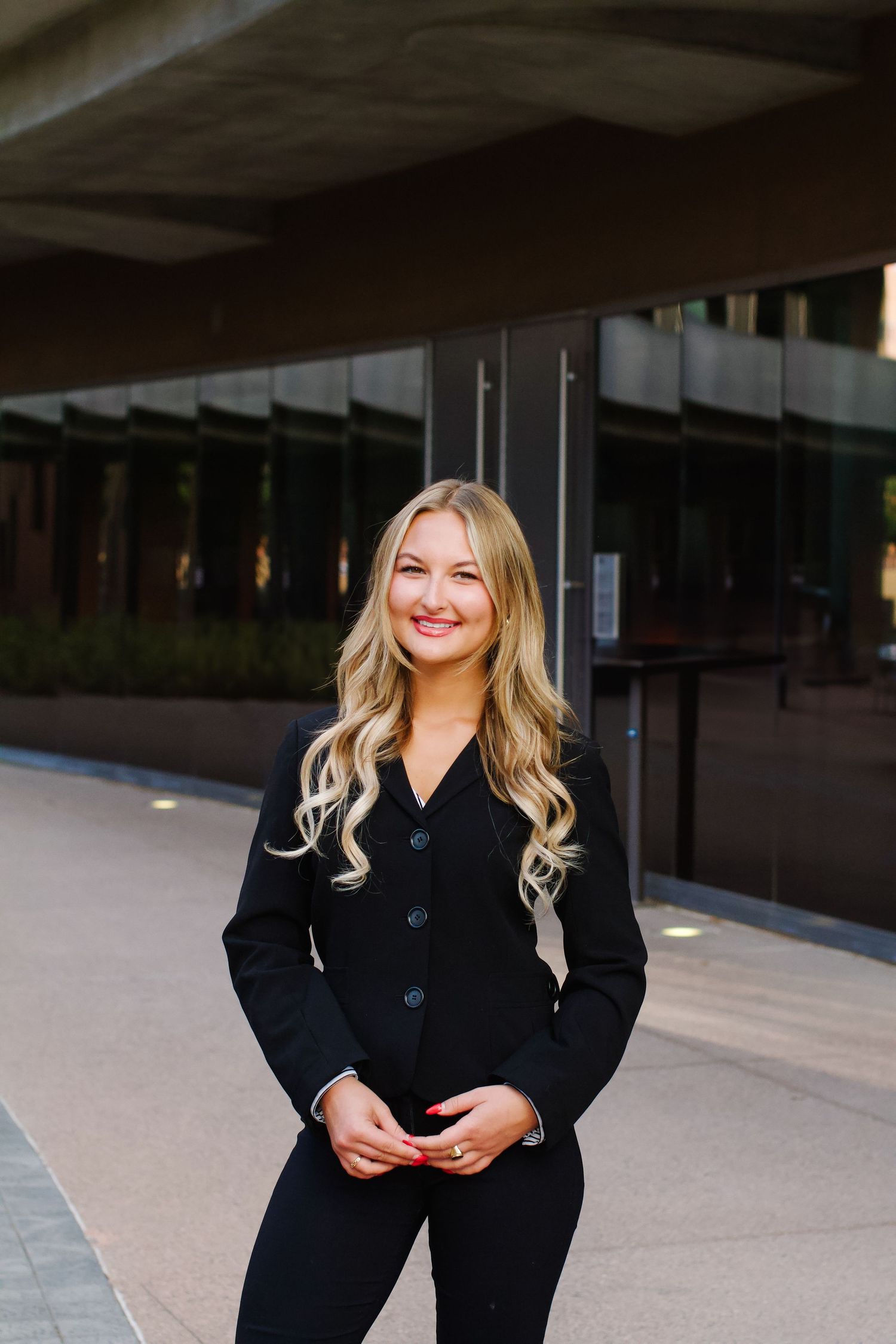 Professional wearing a black blazer poses against an urban backdrop in natural lighting. Tyler Garlej Photography