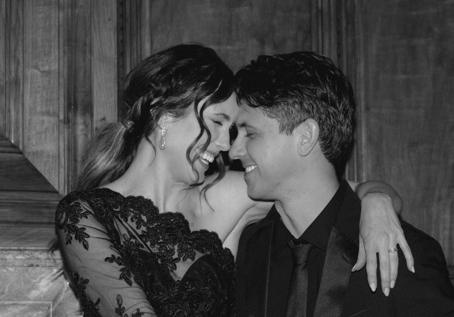 An intimate black and white portrait of a couple sharing a tender moment in formal wear.