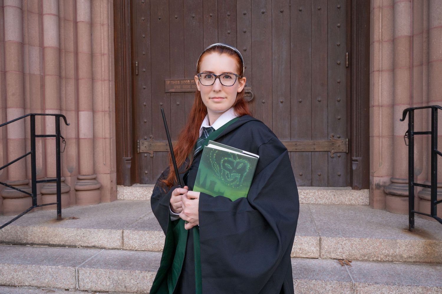 A woman dressed as a Hogwarts student from Harry Potter holding a Harry Potter book