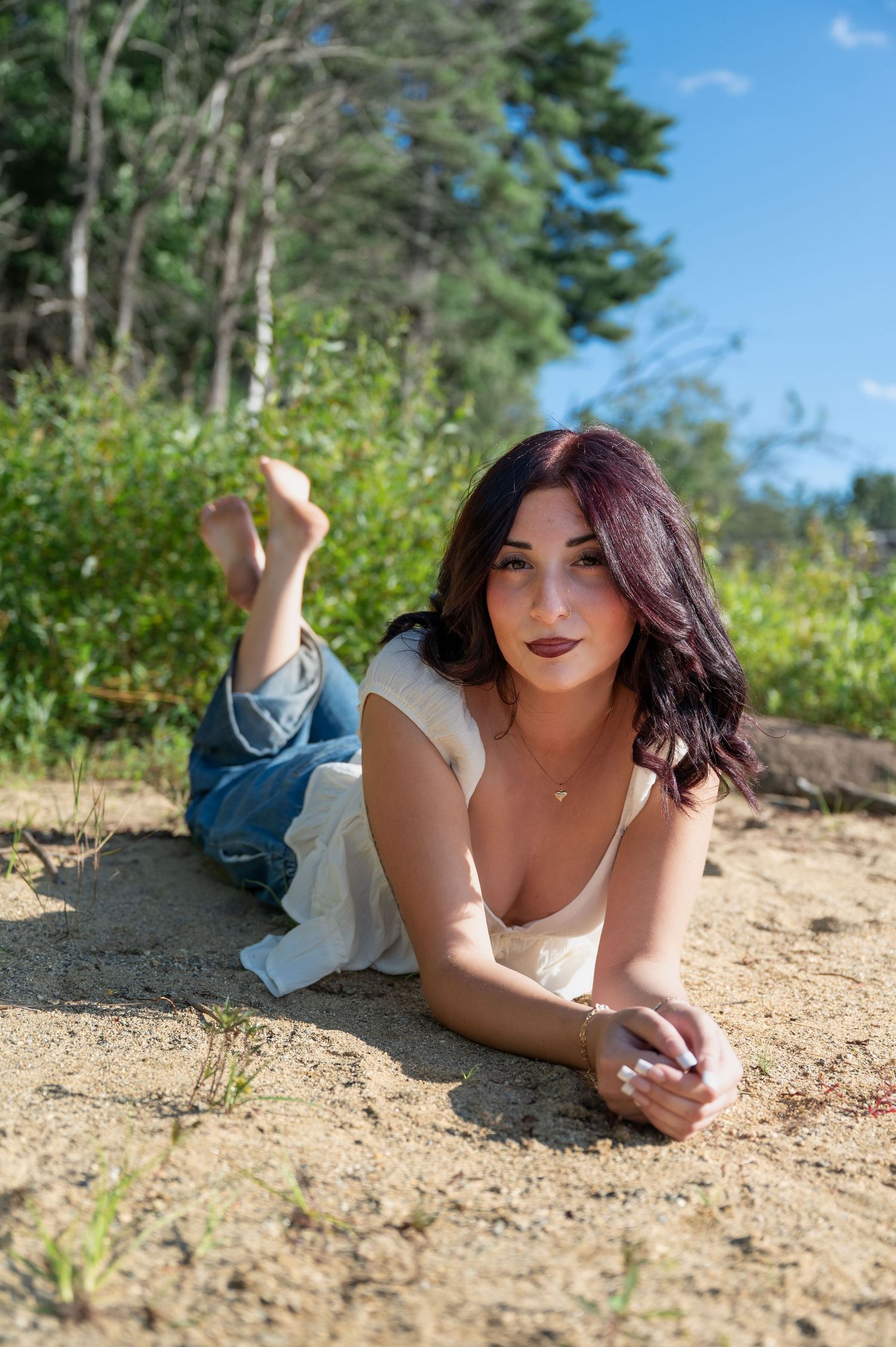 A girl sits on a sunny beach in Surry, New Hampshire. The girl is laying on her stomach.