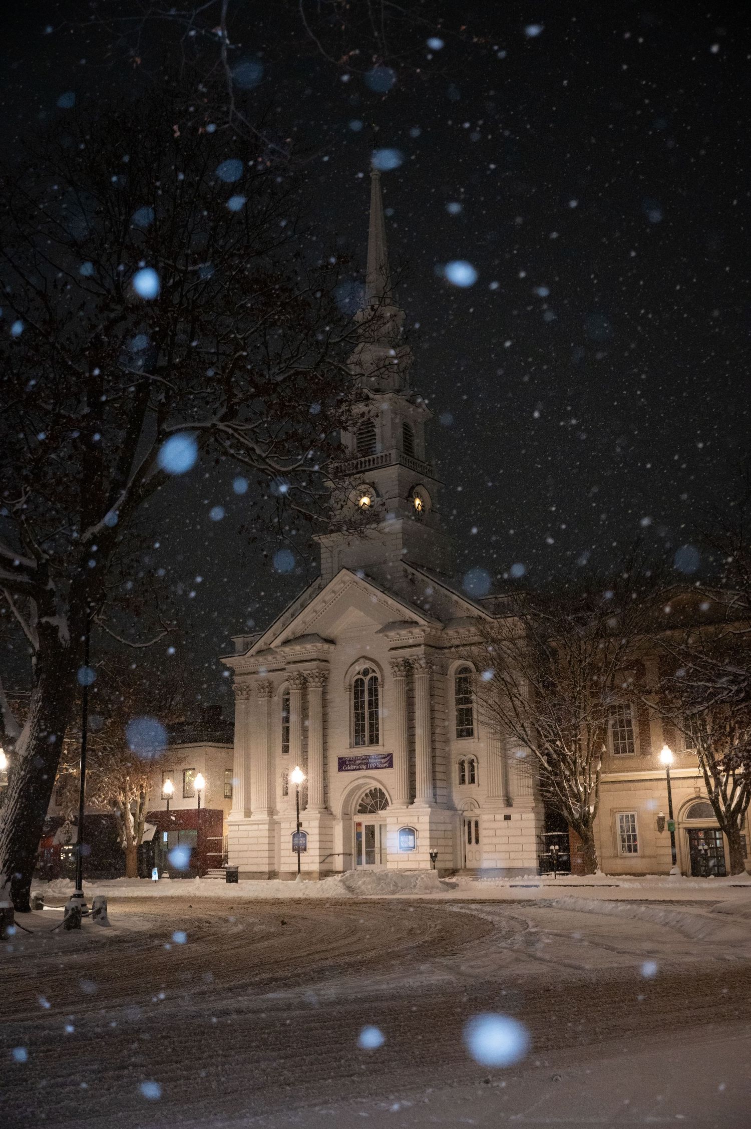 A natural and true to color photo of a snowy night in downtown Keene, New Hampshire