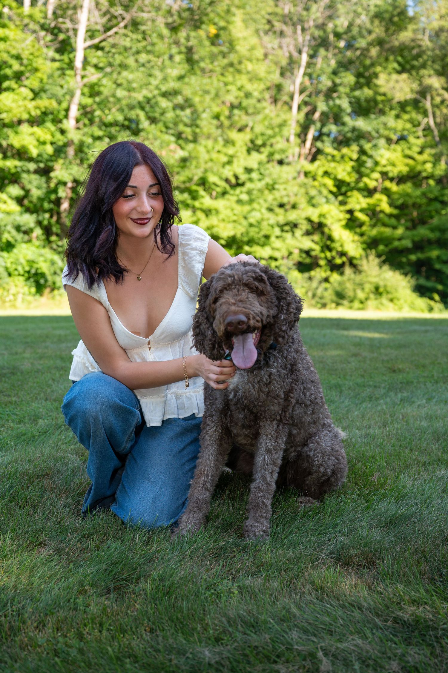 A high school girl sits and poses with her dog for a portrait session in Surry, New Hampshire.