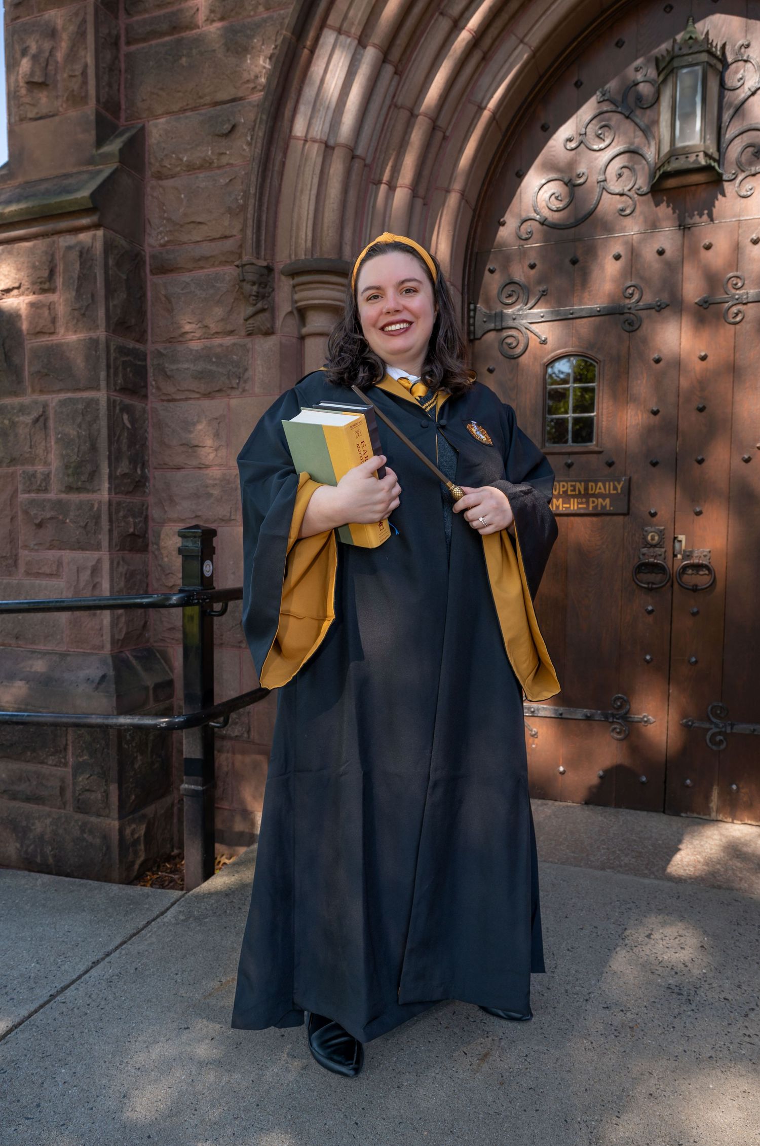 A woman dressed as a Hogwarts student from Harry Potter holding a Harry Potter book