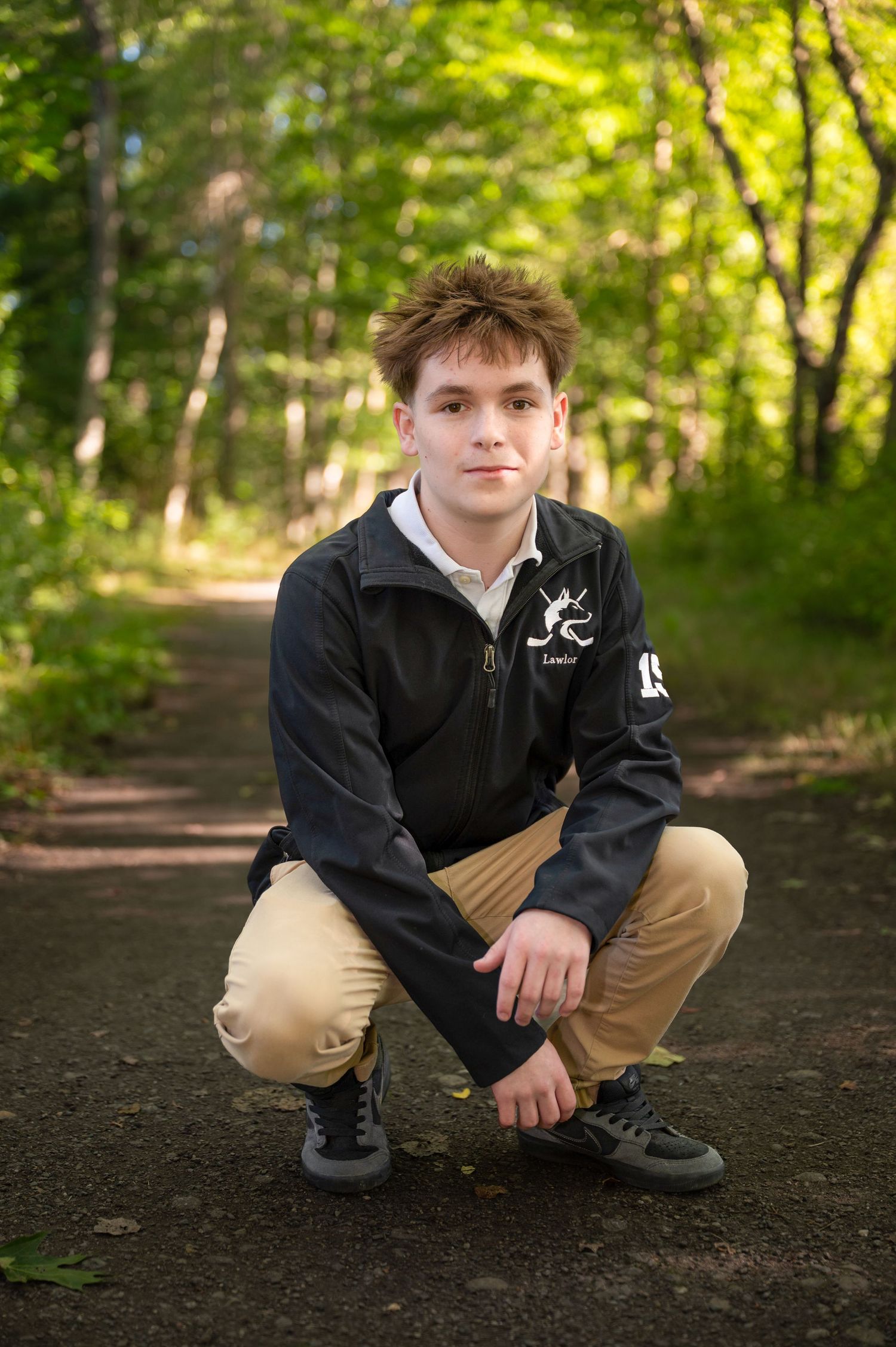 A high school senior poses for a senior portrait in the woods near the Ashuelot River.
