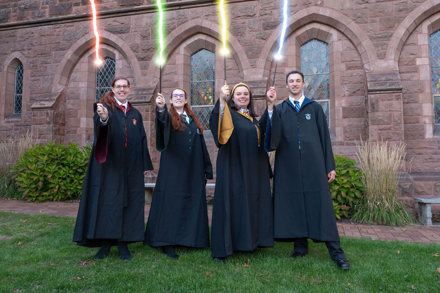 4 friends dressed as Hogwarts students from Harry Potter casting spells pose for a true to color photo at Mt. Holyoke College.