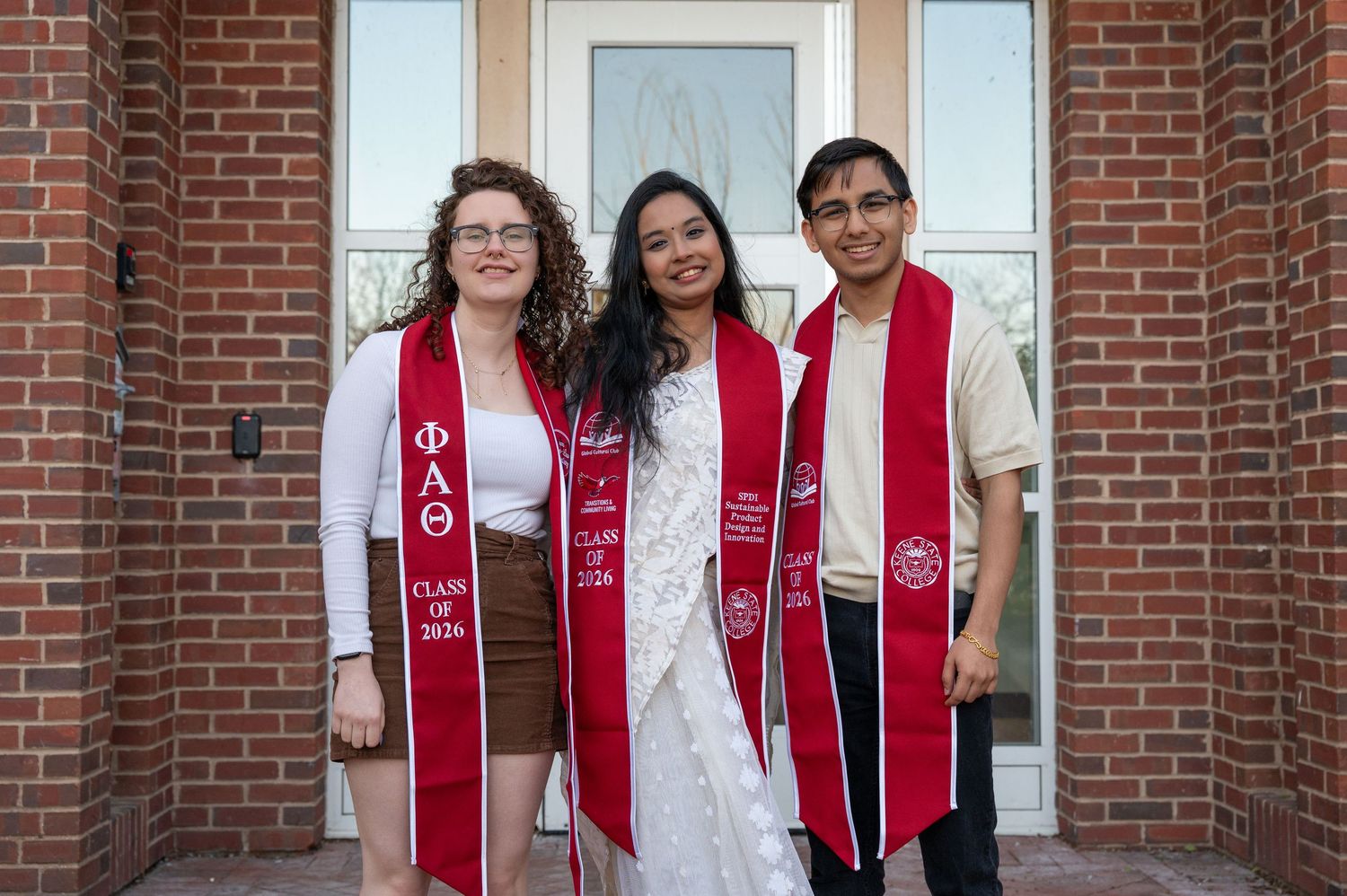 A group of Keene State College graduates posing for true to color photo for a cap & gown photo shoot.