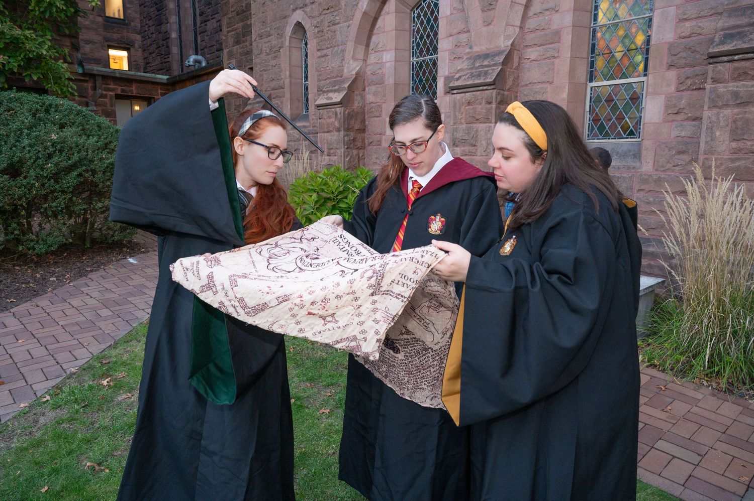 3 girls dressed as Hogwarts students reading the Marauders Map at Mt. Holyoke College.