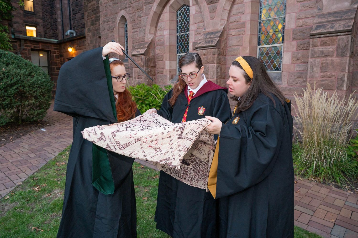 3 girls dressed as Hogwarts students reading the Marauders Map at Mt. Holyoke College.