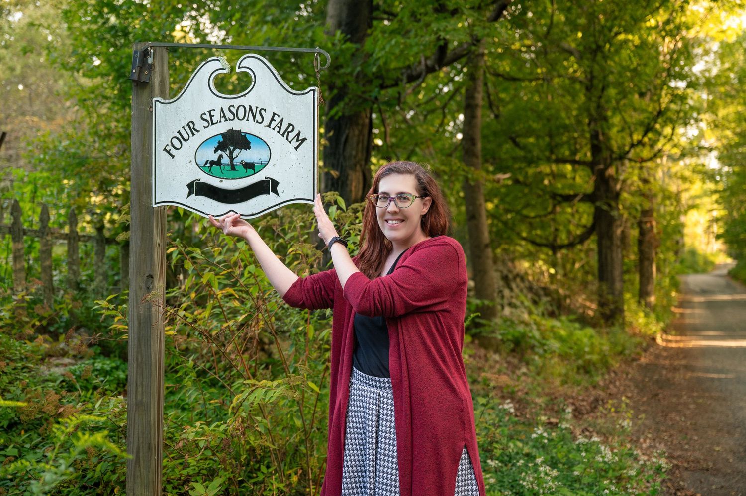 A woman standing and holding a sign at a farm in Fitzwilliam, New Hampshire.
