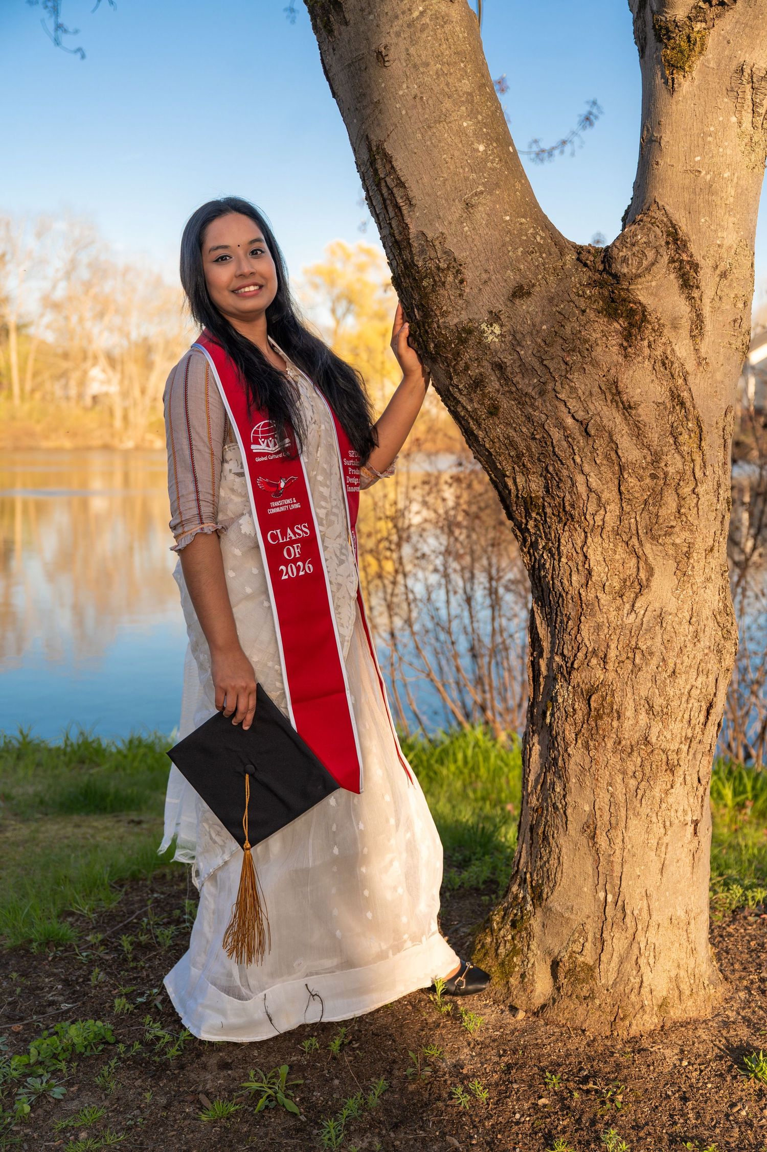 A class of 2026 graduate posing for a true to color style photo at sunset at Keene State graduate.