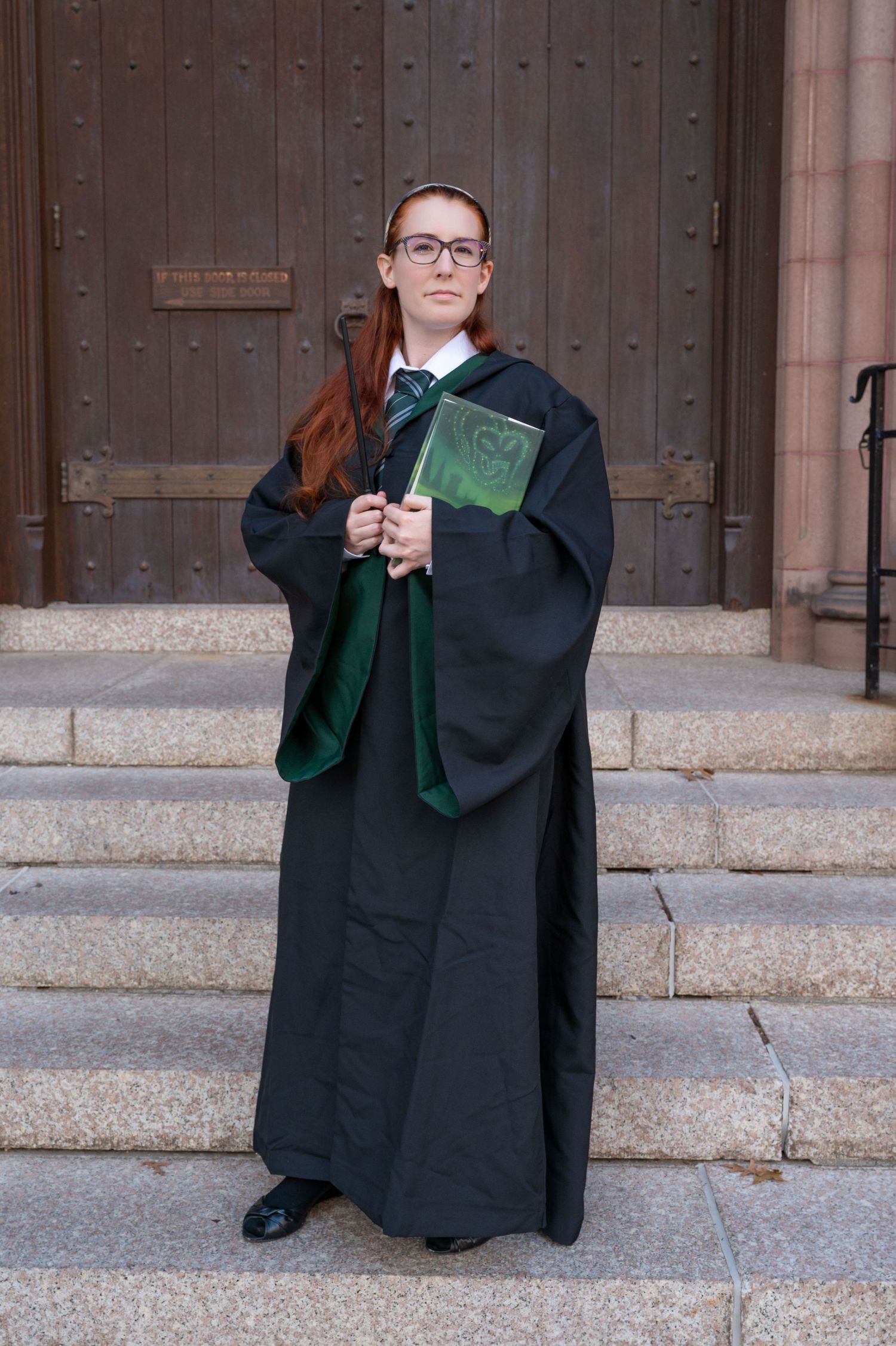 A woman dressed as a Hogwarts student from Harry Potter holding a Harry Potter book