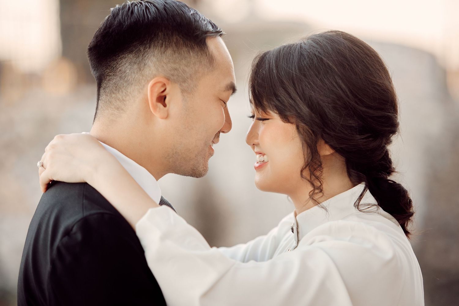 Romantic couple sharing a tender moment, smiling at each other in a close embrace during an engagement photo session.