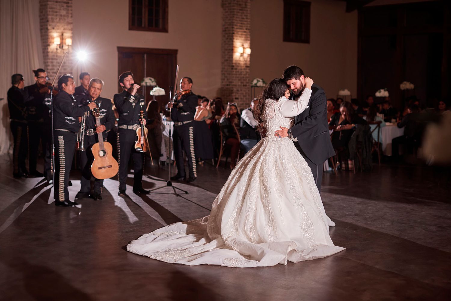 Bride and groom share first dance with mariachi band performing at elegant wedding reception.