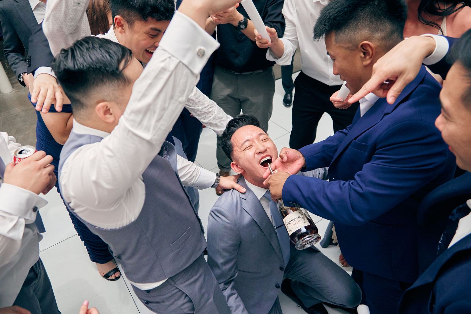 Groom laughs joyfully as groomsmen celebrate together in an energetic group moment at wedding.