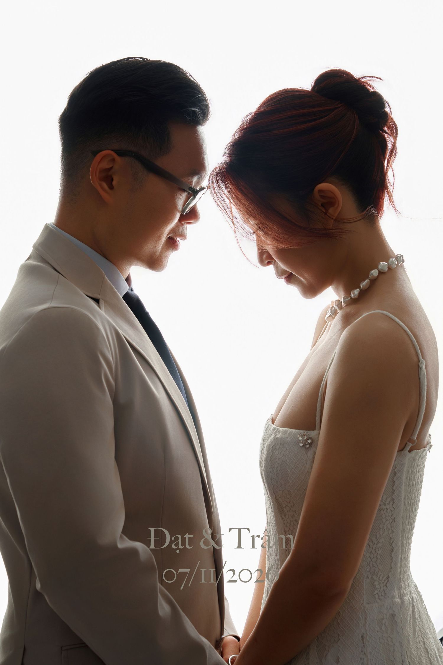 Romantic wedding couple in silhouette, groom in beige suit and bride in white dress holding hands, dated 07/11/2026.